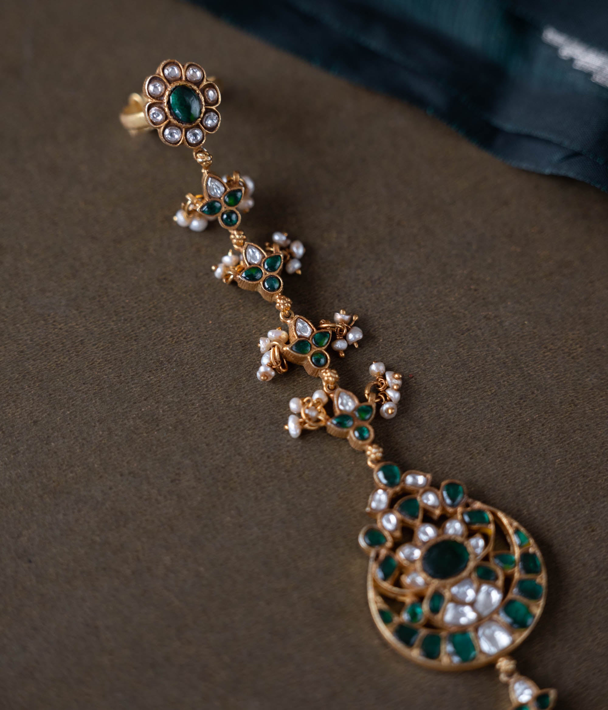 Handmade 92.5 sterling silver and 22ct gold-plated Eshna Emerald Haathphool with white and green Kundan stones, intricate floral motifs, and delicate pearls, exuding royal elegance.