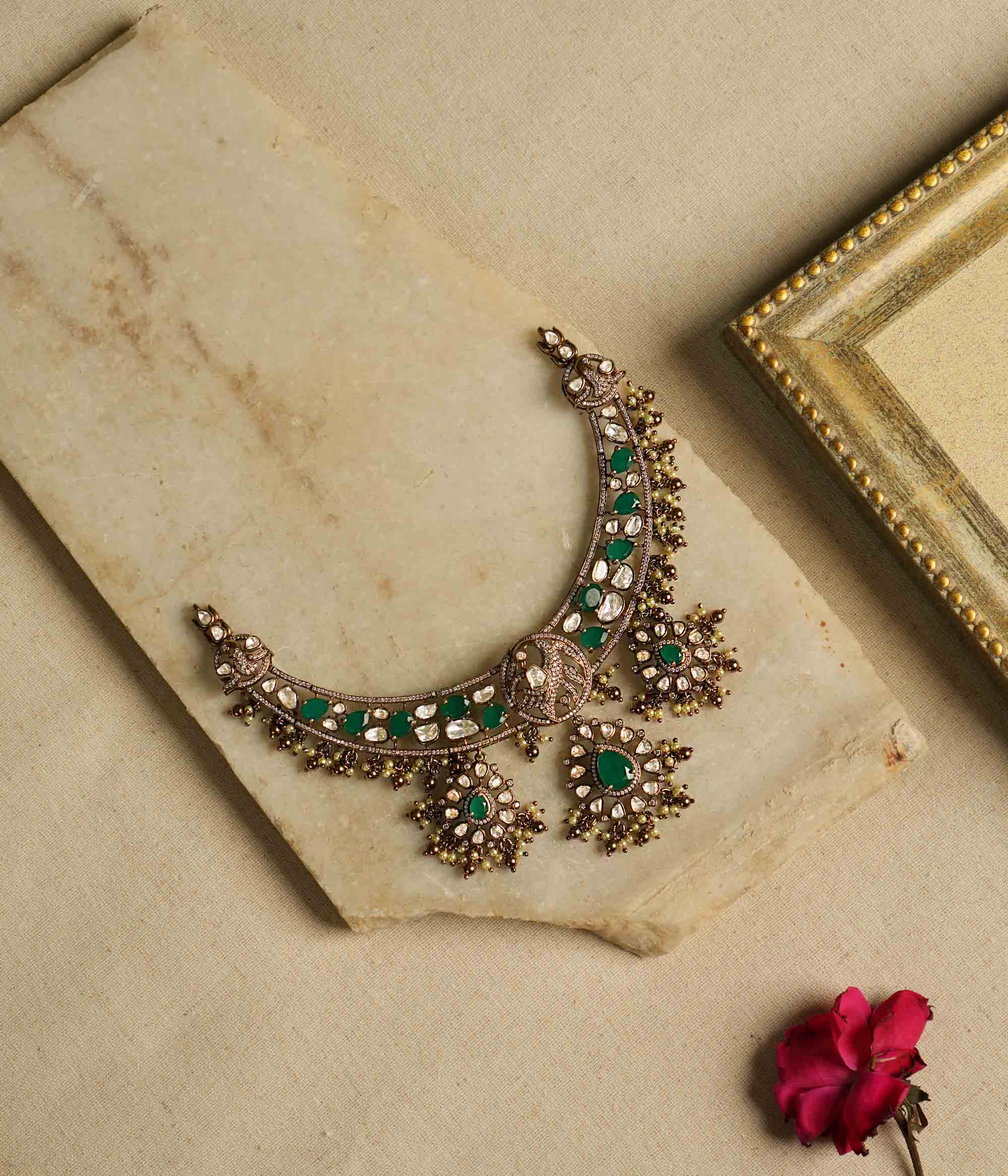 Victorian opulence reborn! This gold-plated silver choker necklace features a dazzling combination of CZ stones, green gemstones, and polki stones. The chain is adorned with polki and green gemstones, while the pendant mirrors the same design, gracefully accented with delicate pearl drops. A timeless blend of heritage and luxury, redefined for modern elegance.