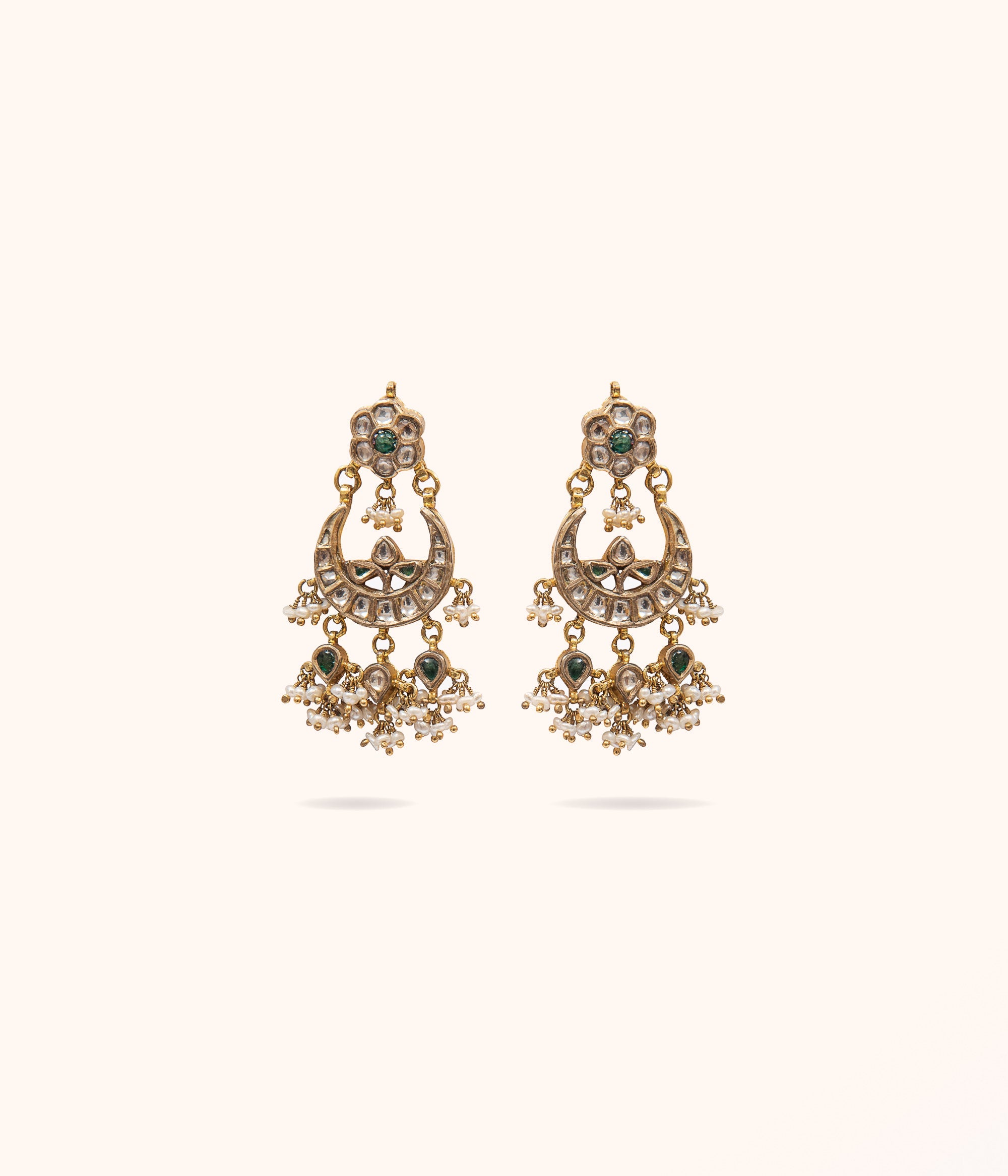 Chandbali earrings crafted in a floral and moon design, featuring emerald stones, white pearls, and sparkling white sapphire, elegantly gold-plated for a timeless and sophisticated look.