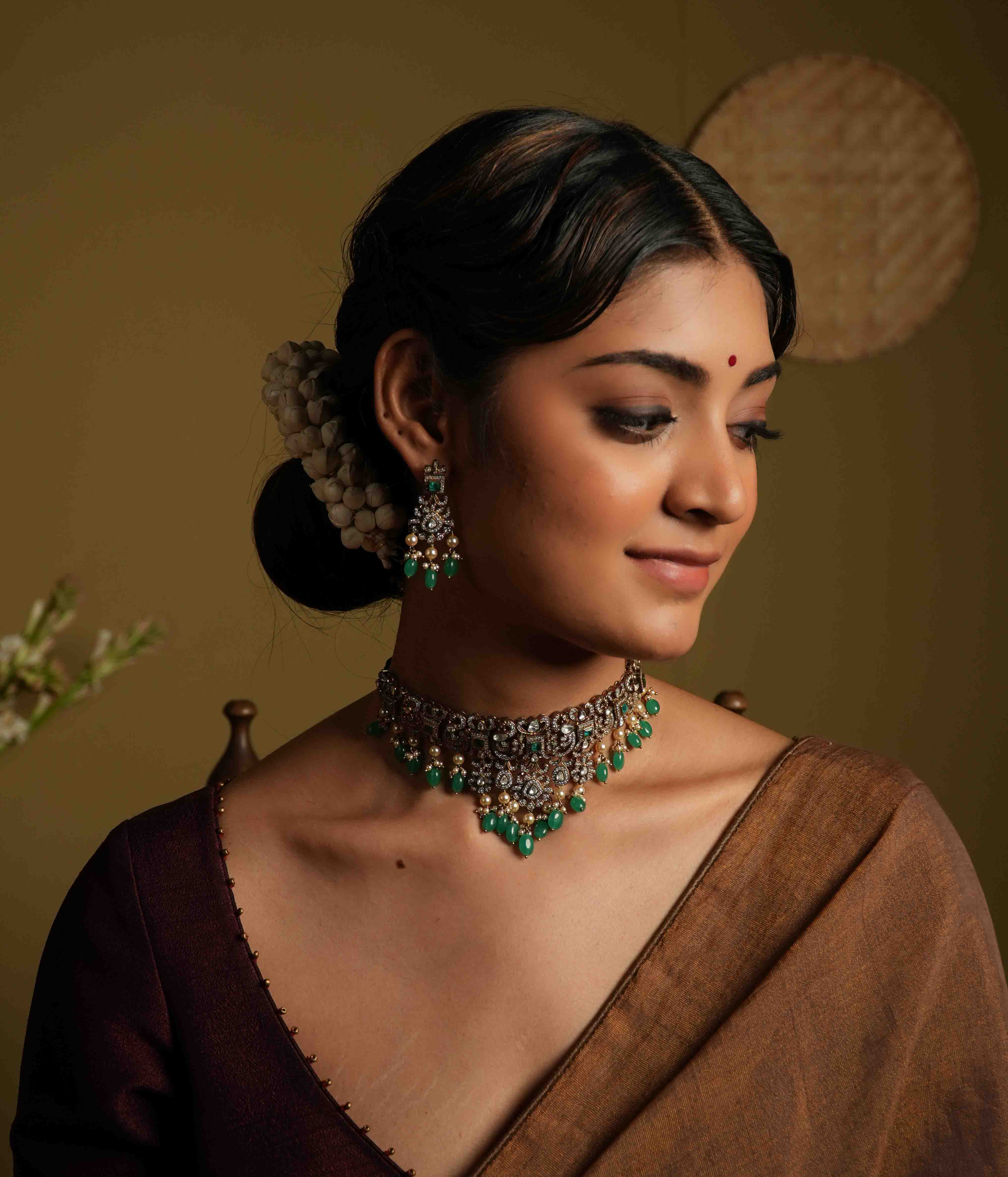 These intricate drop earrings, crafted from 92.5 sterling silver and featuring Bombay screw fastenings, showcase moissanite and bold green gemstones, complemented by delicate pearl dangles that evoke the opulence of a Victorian era.