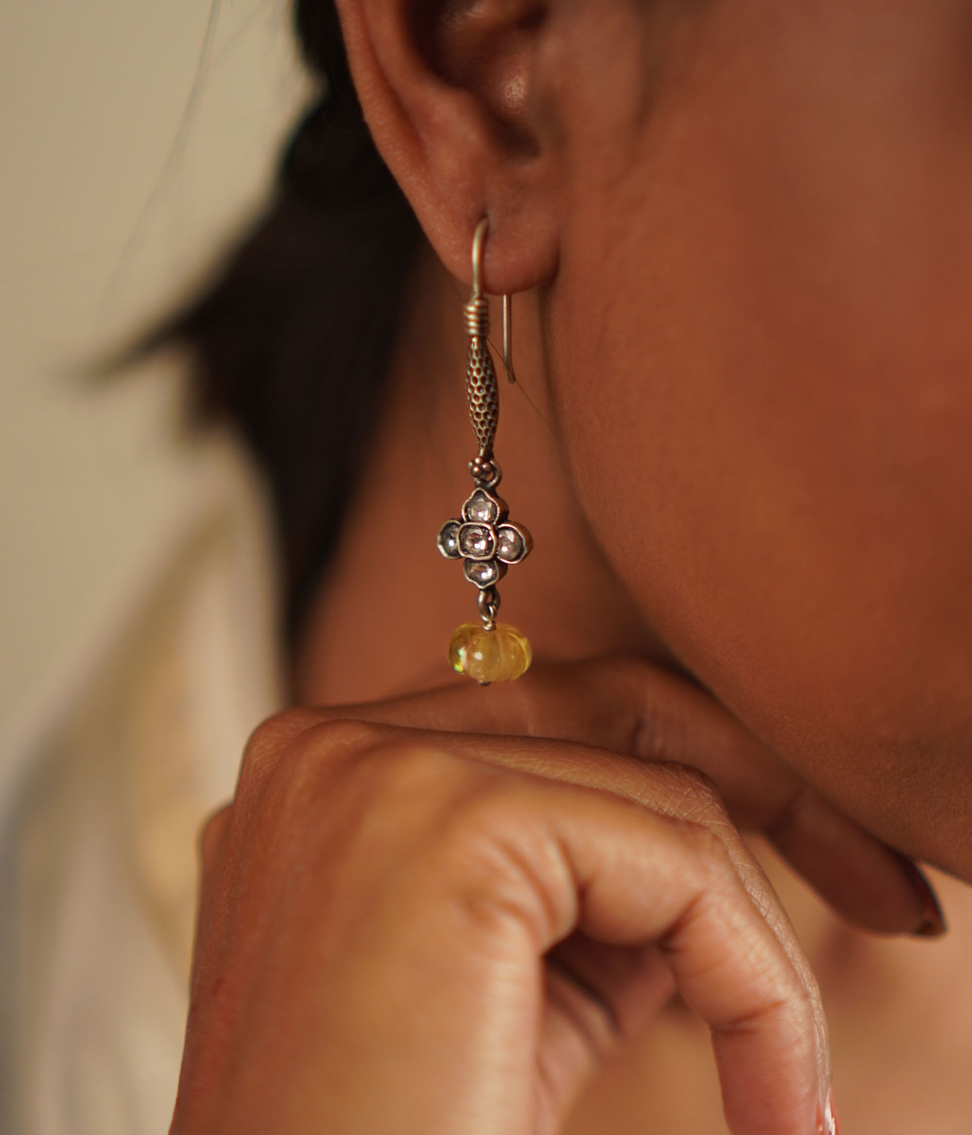 The Gatha earrings, crafted in oxidized silver, showcase delicate white kundan stones and vibrant yellow beads. With their elegant drop design, they exude a timeless allure, embracing the charm of artisanal craftsmanship and the beauty of handcrafted uniqueness.
