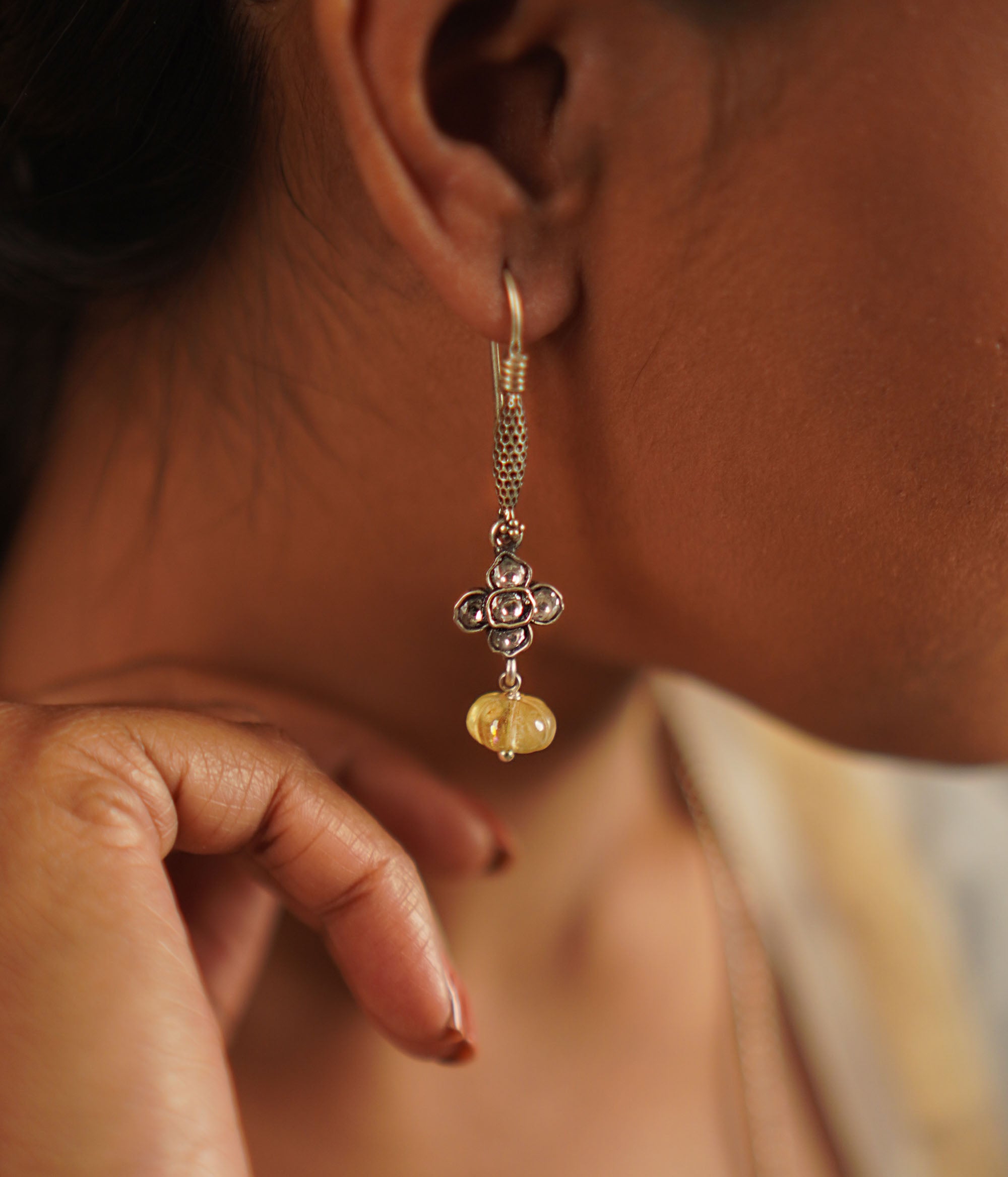 The Gatha earrings, crafted in oxidized silver, showcase delicate white kundan stones and vibrant yellow beads. With their elegant drop design, they exude a timeless allure, embracing the charm of artisanal craftsmanship and the beauty of handcrafted uniqueness.