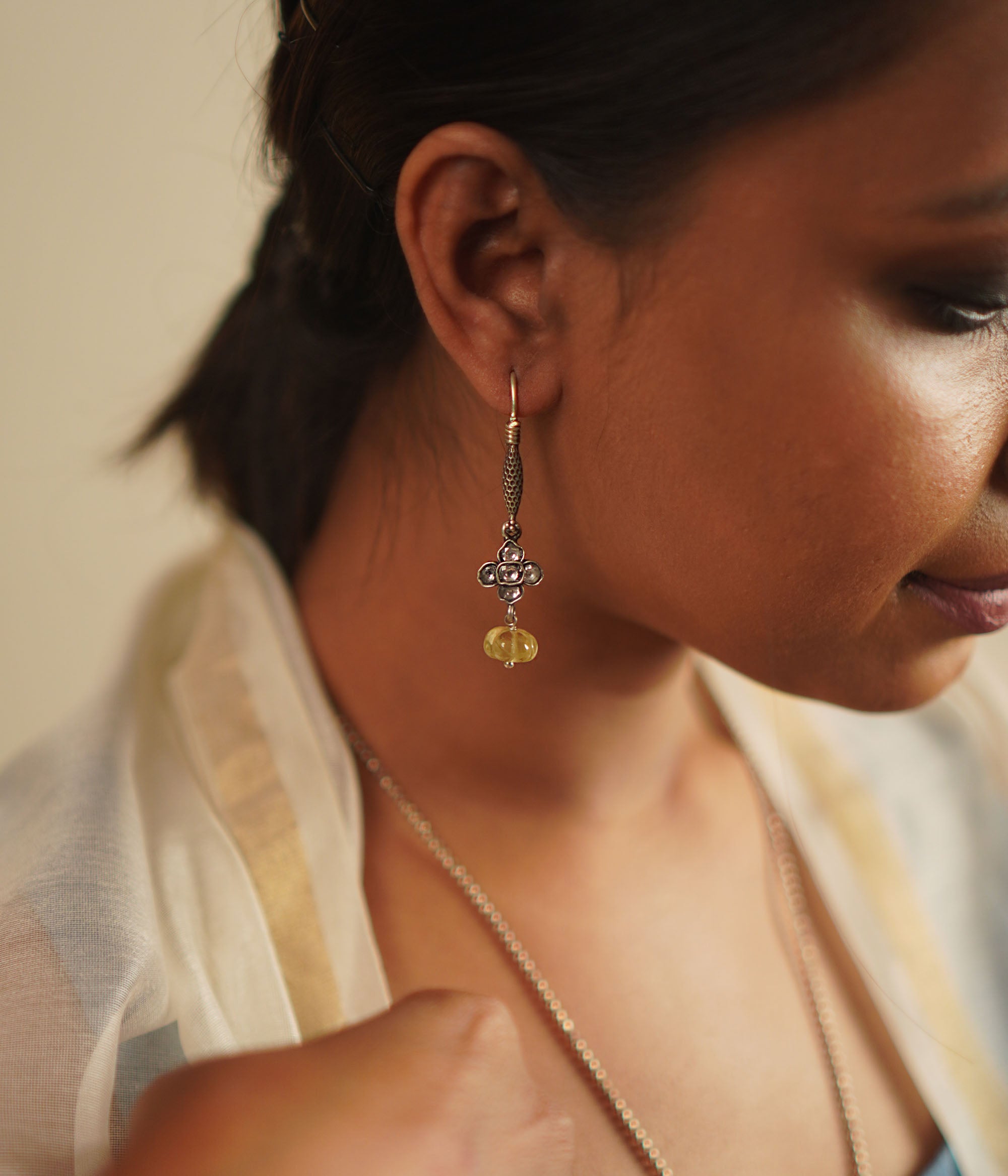 The Gatha earrings, crafted in oxidized silver, showcase delicate white kundan stones and vibrant yellow beads. With their elegant drop design, they exude a timeless allure, embracing the charm of artisanal craftsmanship and the beauty of handcrafted uniqueness.