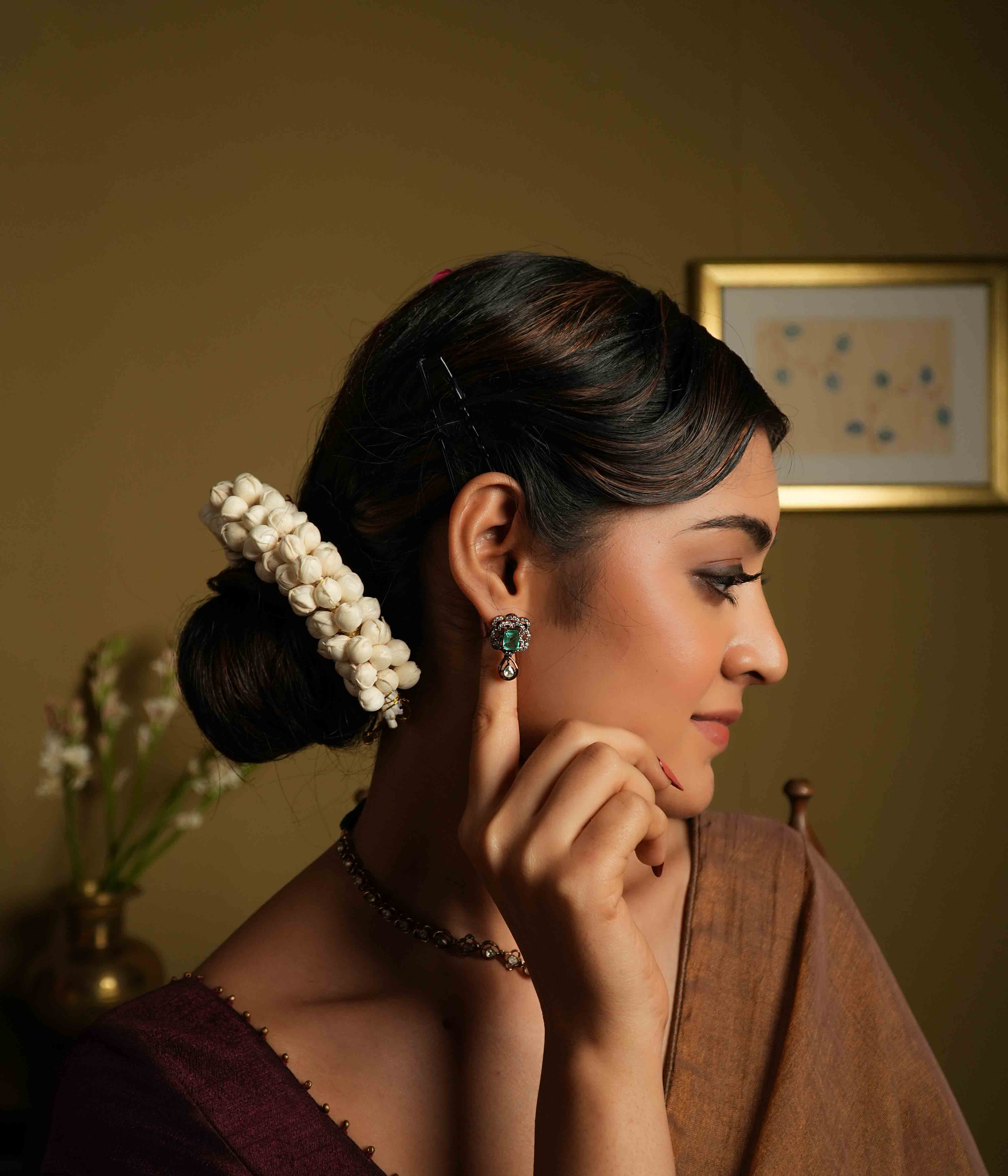 Evoking Victorian elegance, these handmade ear studs feature moissanite petals embracing a square-cut cultured emerald, with a delicate teardrop polki dangling below. Crafted from 92.5 sterling silver and plated in 22ct gold, these screw-back earrings offer a statement of refined sophistication