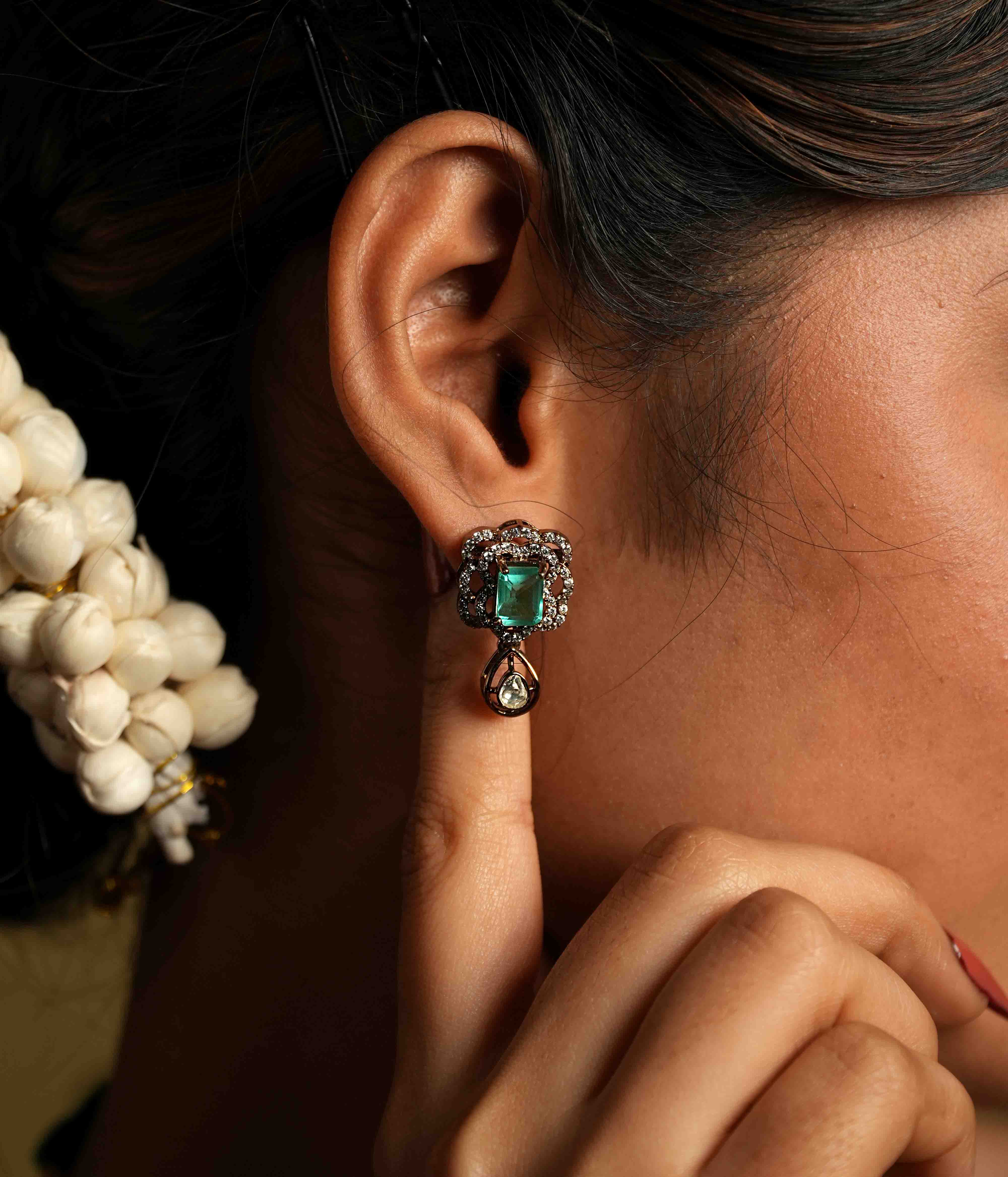 Evoking Victorian elegance, these handmade ear studs feature moissanite petals embracing a square-cut cultured emerald, with a delicate teardrop polki dangling below. Crafted from 92.5 sterling silver and plated in 22ct gold, these screw-back earrings offer a statement of refined sophistication