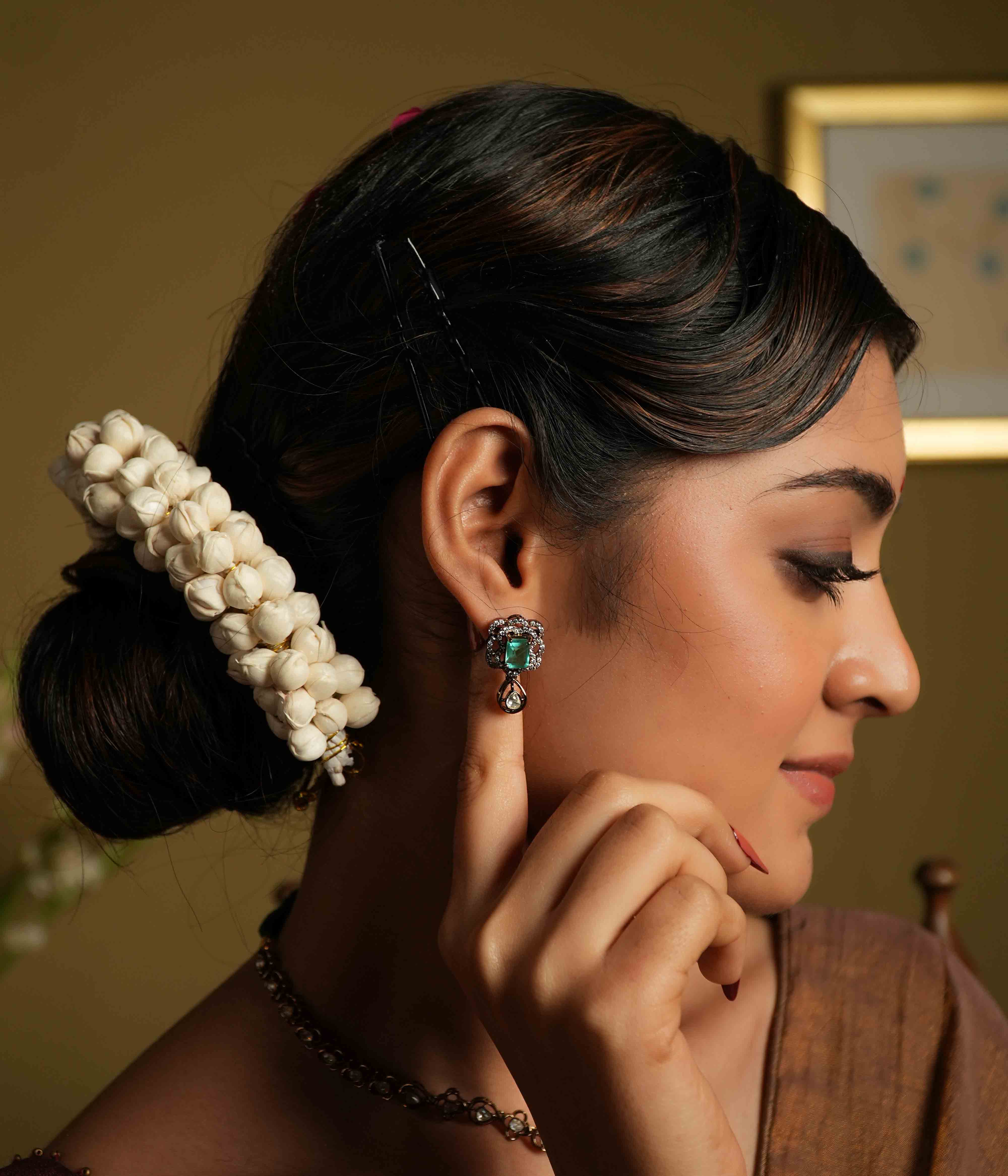 Evoking Victorian elegance, these handmade ear studs feature moissanite petals embracing a square-cut cultured emerald, with a delicate teardrop polki dangling below. Crafted from 92.5 sterling silver and plated in 22ct gold, these screw-back earrings offer a statement of refined sophistication