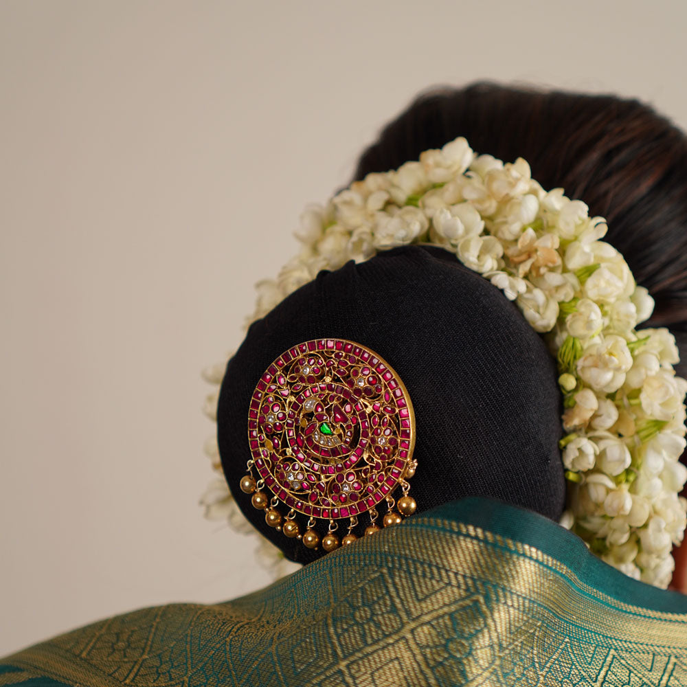 This exquisite hairpin, adorned with red, white, and green kundan stones along with delicate pearls, beautifully reflects Indian heritage. Its handcrafted halo design adds a distinctive touch, celebrating tradition with timeless elegance.