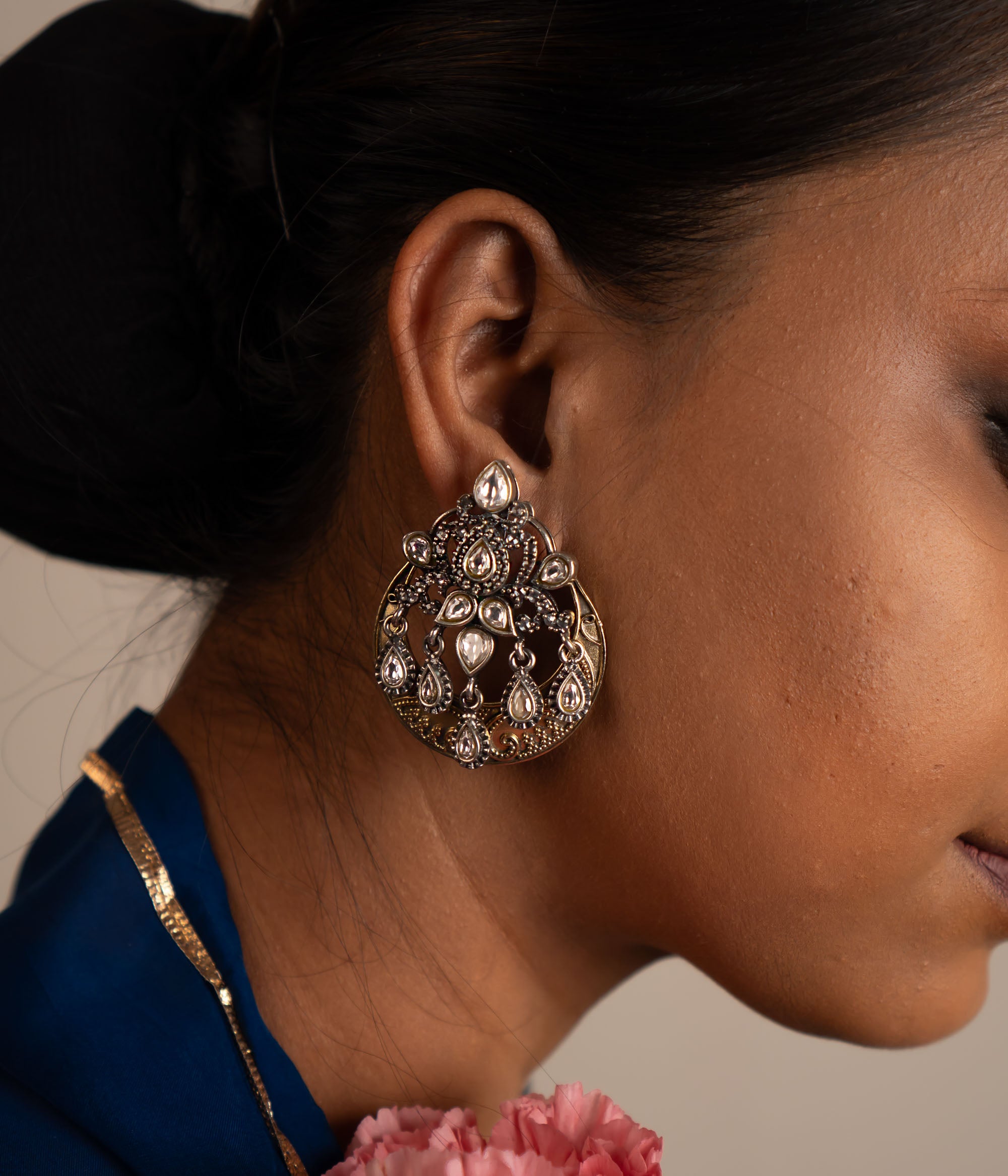 The Gurhal earrings showcase delicate floral patterns in oxidized silver, beautifully enhanced by the intricate brilliance of white Kundan stones.