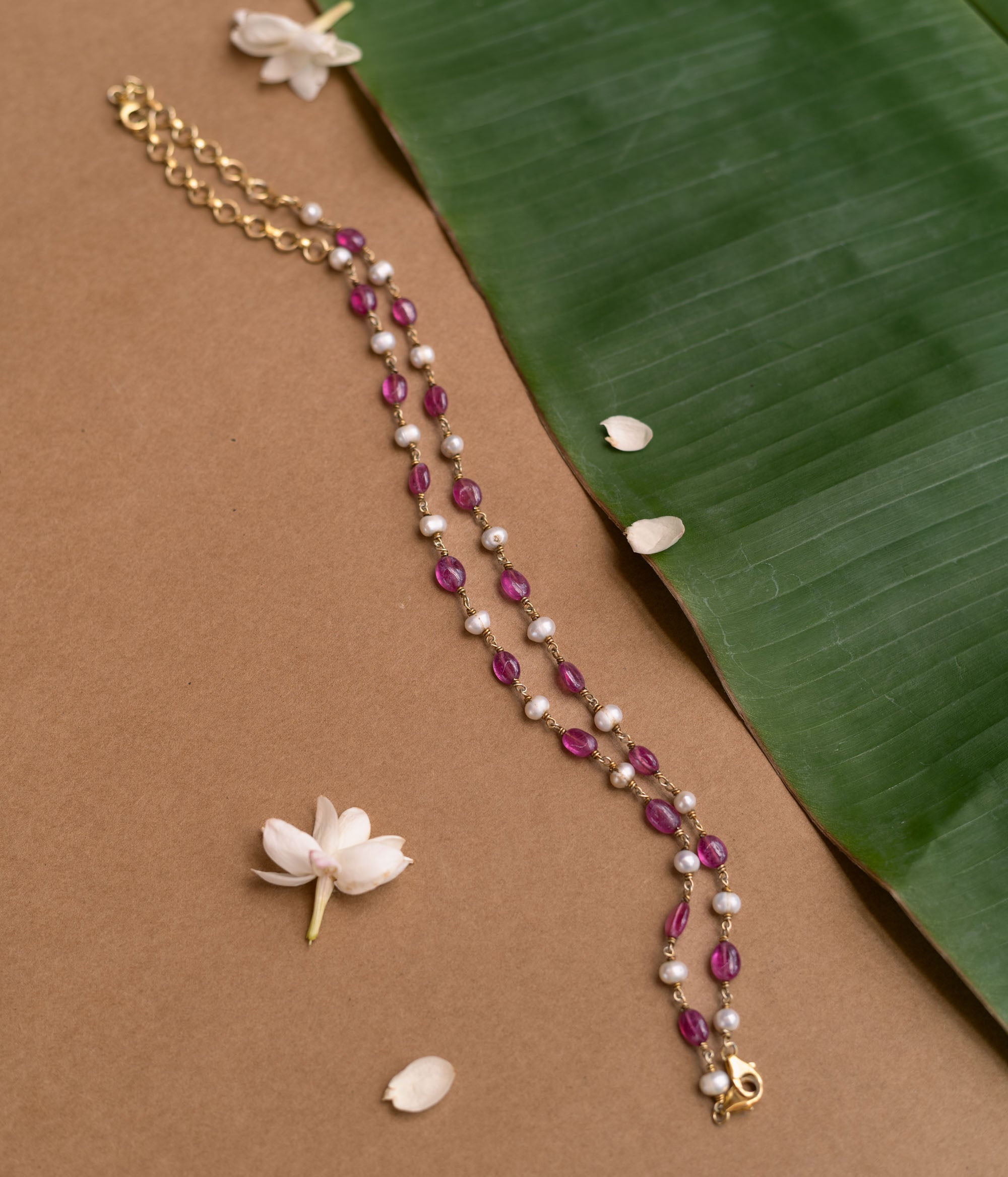 A two-strand necklace with one strand of red beads and the other of pearls.