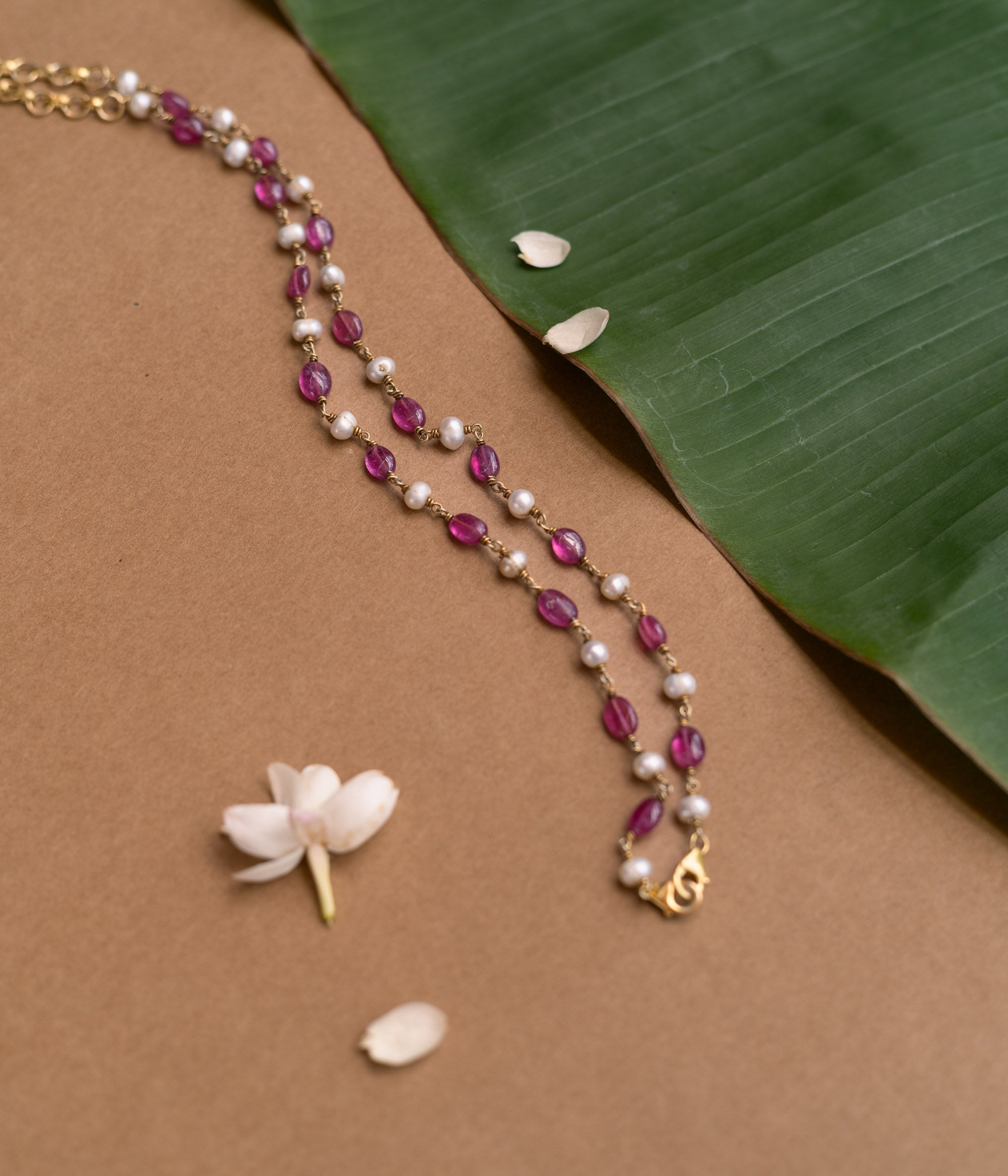 A two-strand necklace with one strand of red beads and the other of pearls.