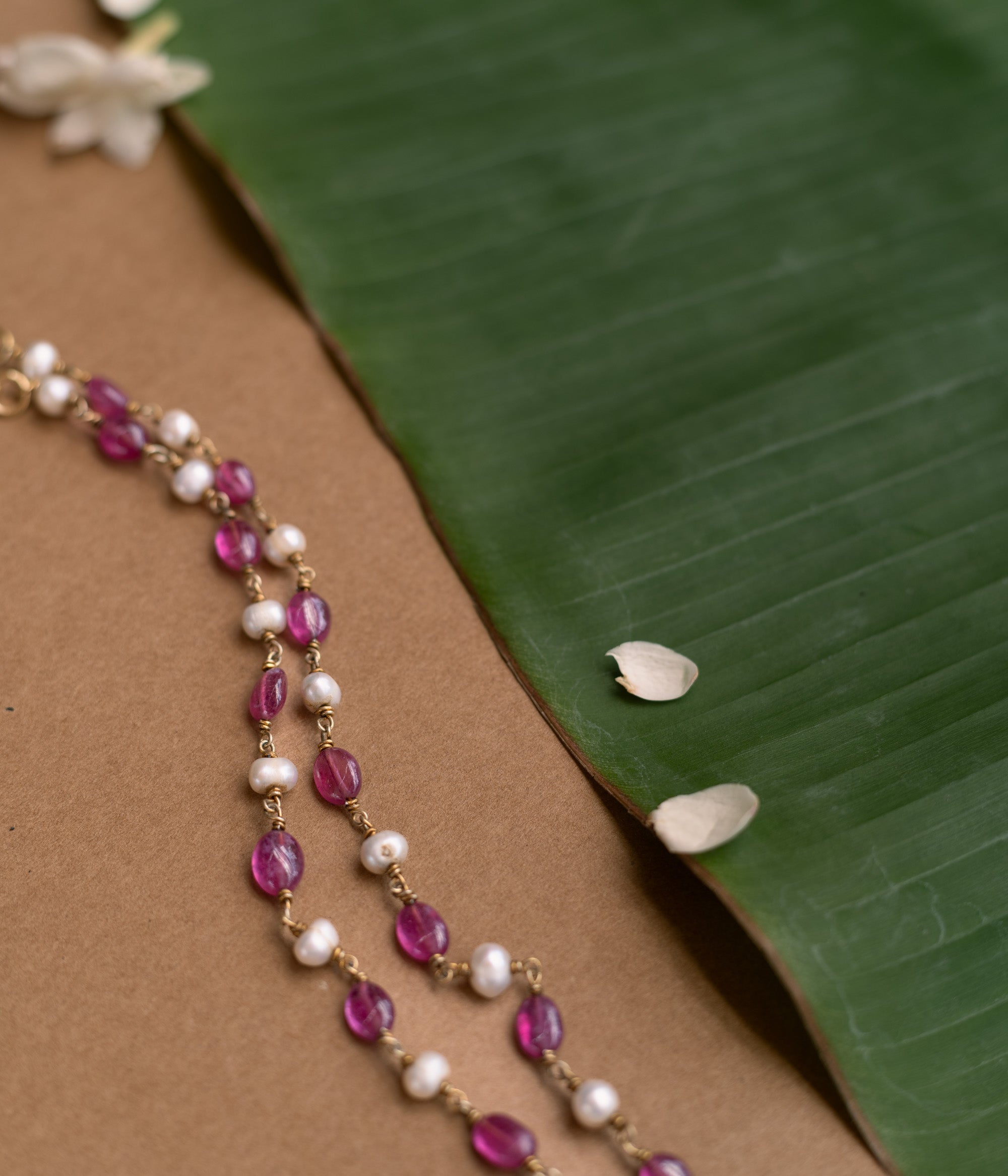 A two-strand necklace with one strand of red beads and the other of pearls.
