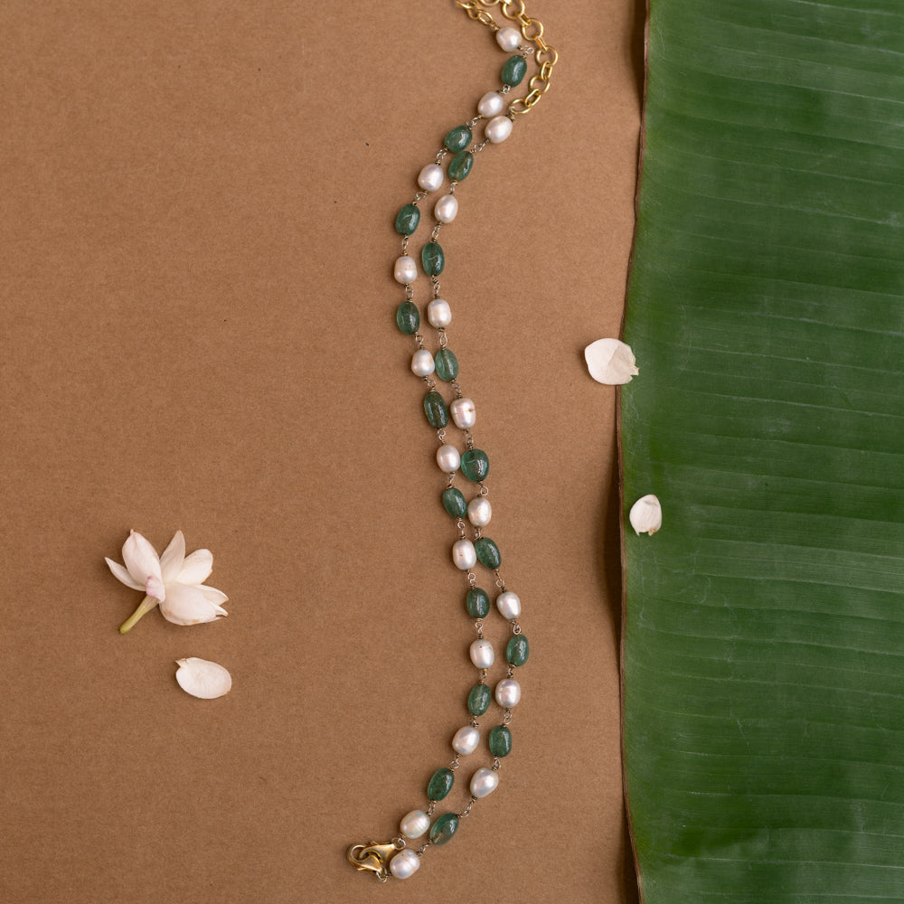 A long necklace made of alternating green and white beads.