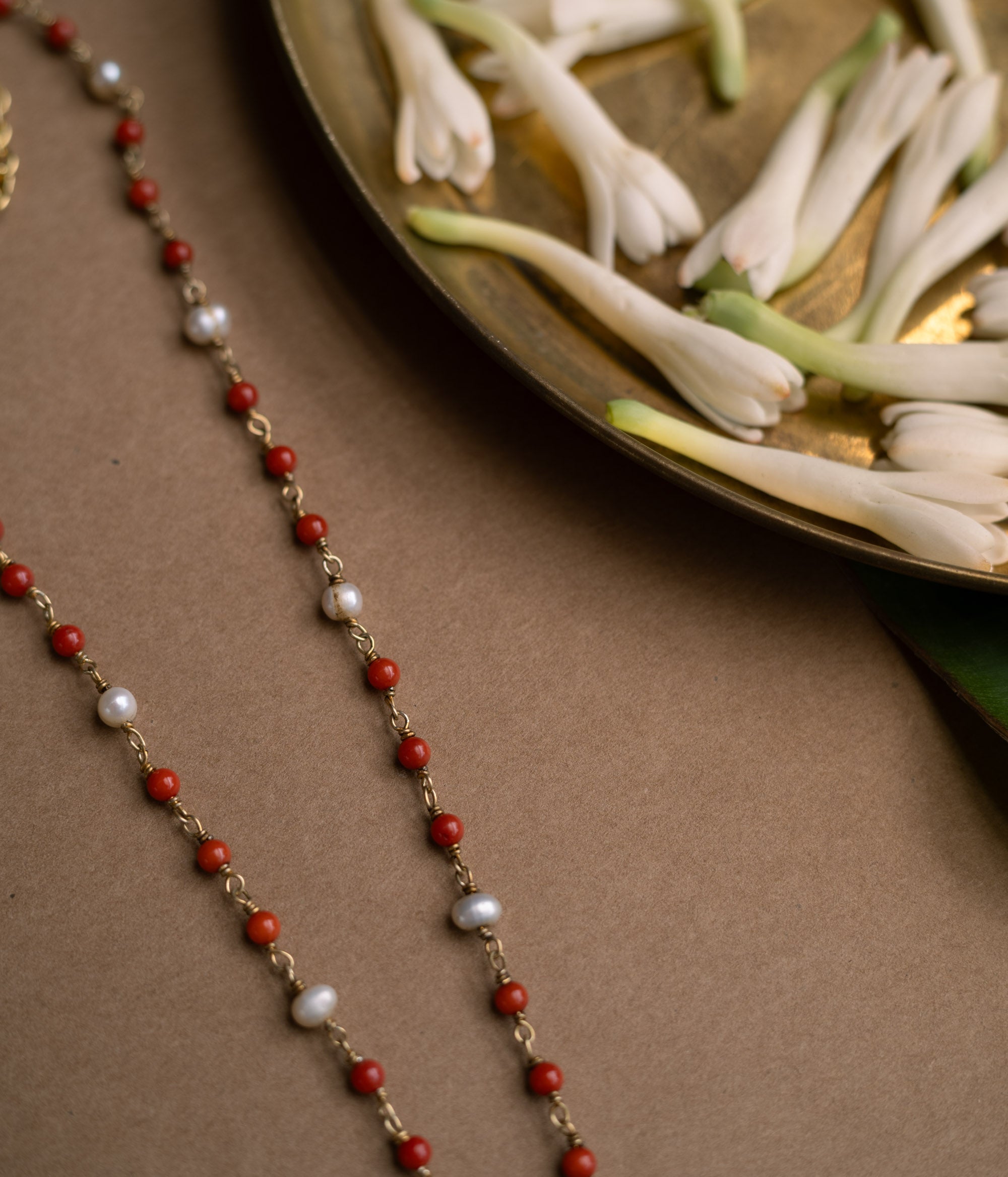 A three-tiered chain with one strand of red beads, one of green beads, and a final strand of pearls.