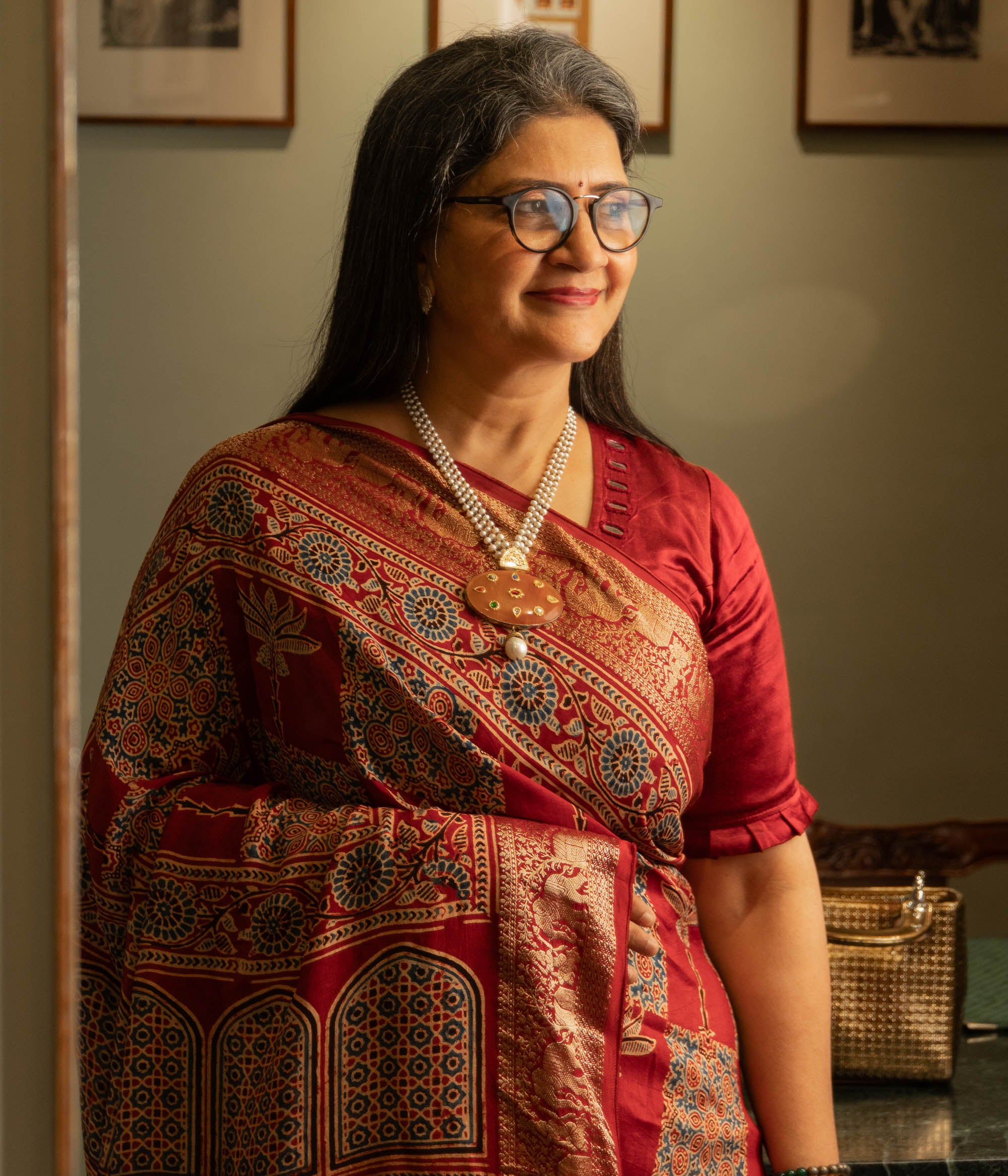 Woman wearing a terracotta pendant necklace with pearl strings from the Hue Collection.