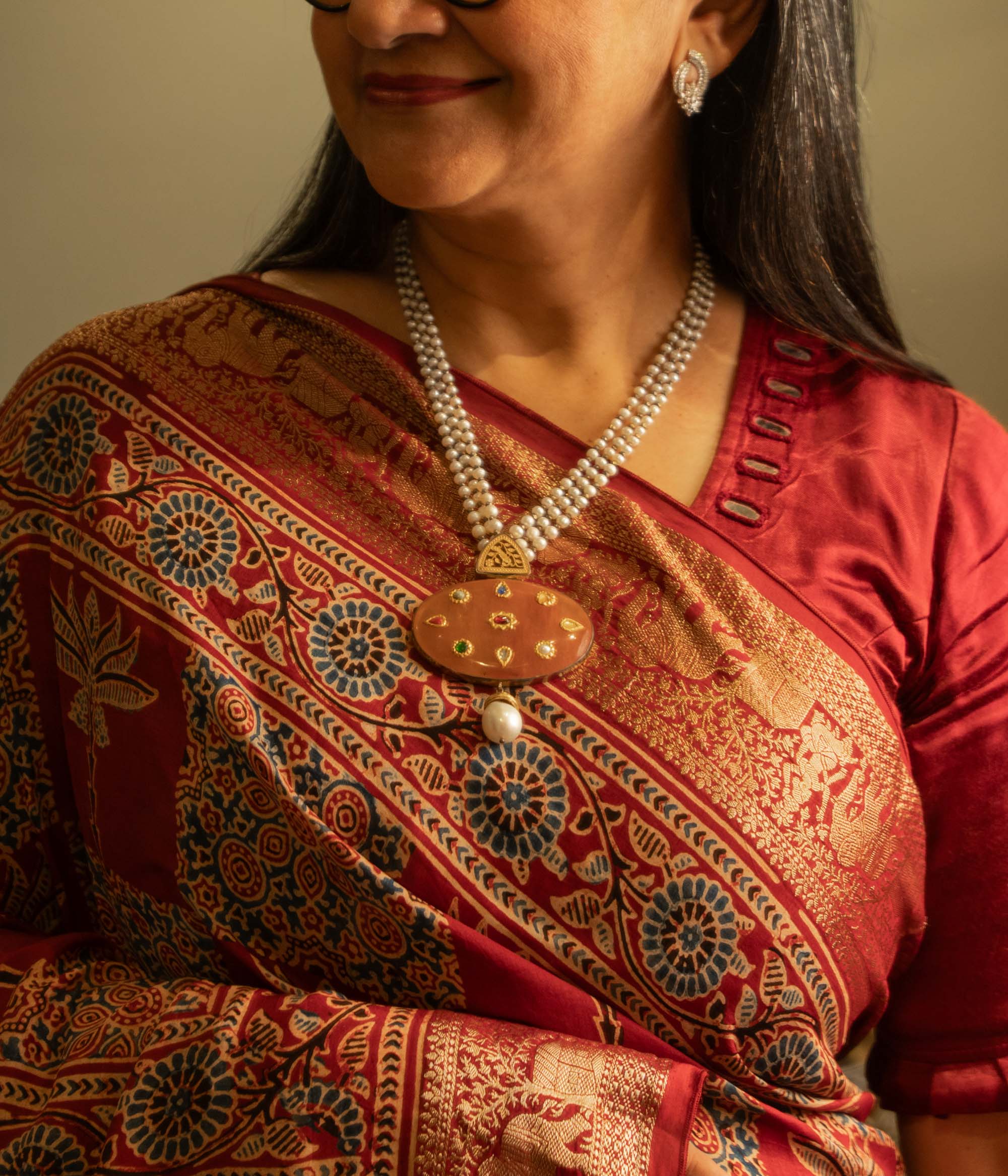 Woman wearing a terracotta pendant necklace with pearl strings from the Hue Collection.