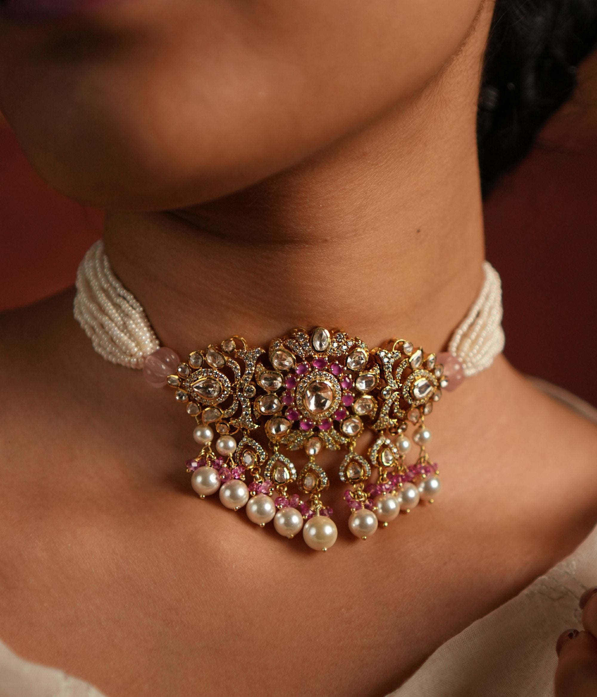 Elegant layered pearl choker featuring a floral-designed pendant adorned with Moissanite Polki Stones, CZ Stones, and Pink Stones. The pendant is beautifully accented with delicate drops of Rose Quartz and pearls, adding a touch of sophistication and grace.