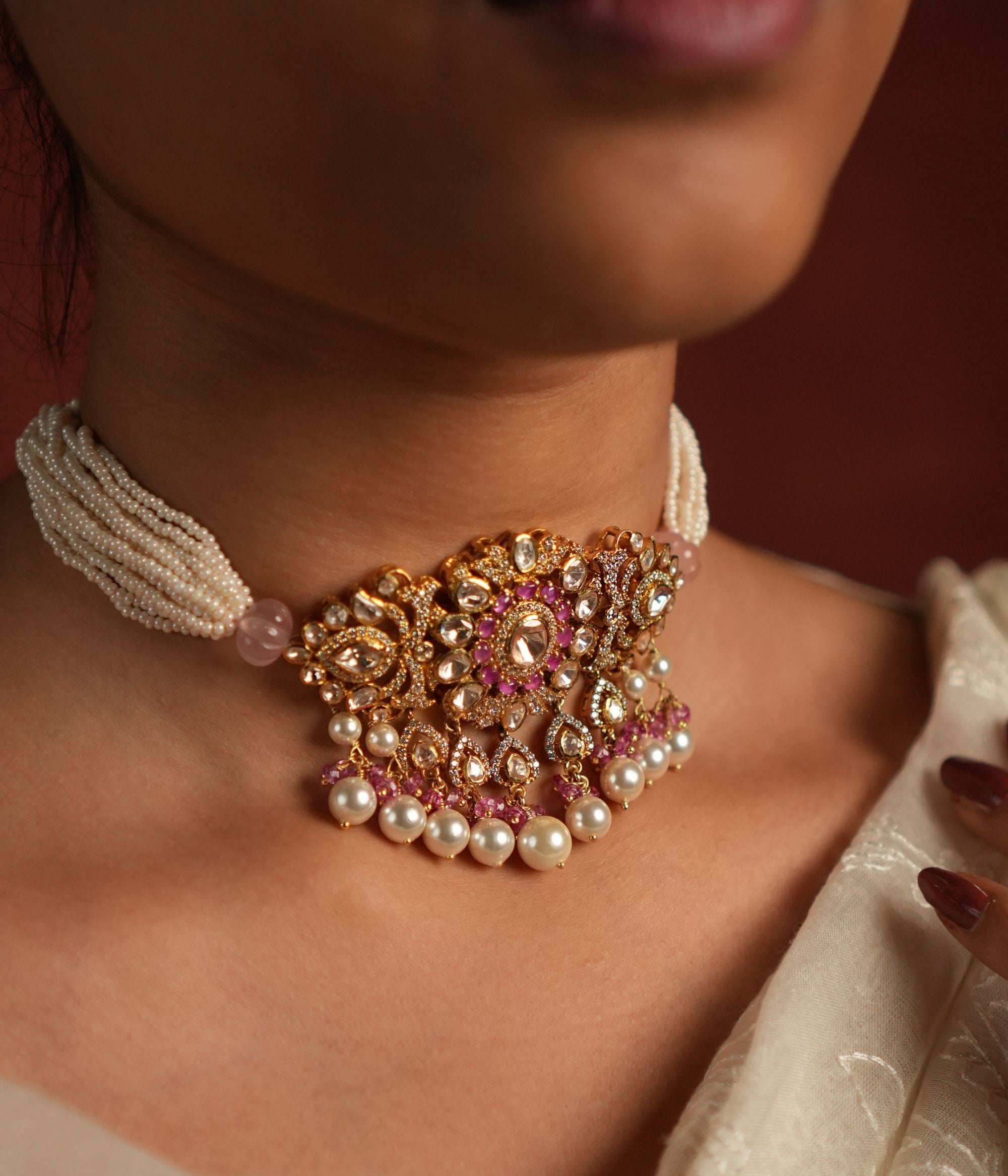 Elegant layered pearl choker featuring a floral-designed pendant adorned with Moissanite Polki Stones, CZ Stones, and Pink Stones. The pendant is beautifully accented with delicate drops of Rose Quartz and pearls, adding a touch of sophistication and grace.