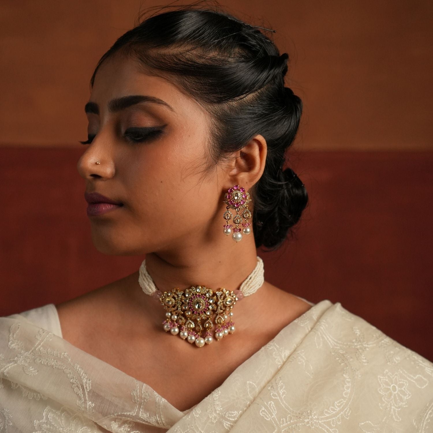 A stunning gold-plated silver dangler earring featuring Moissanite Polki stones and Rose Quartz. The stud showcases a delicate floral design crafted with Rose Quartz, while the elegant drop is adorned with a shimmering Polki stone covered by cz stones , gracefully complemented by white pearls and soft pink beads. This exquisite piece adds a touch of elegance and charm, perfect for a timeless look.