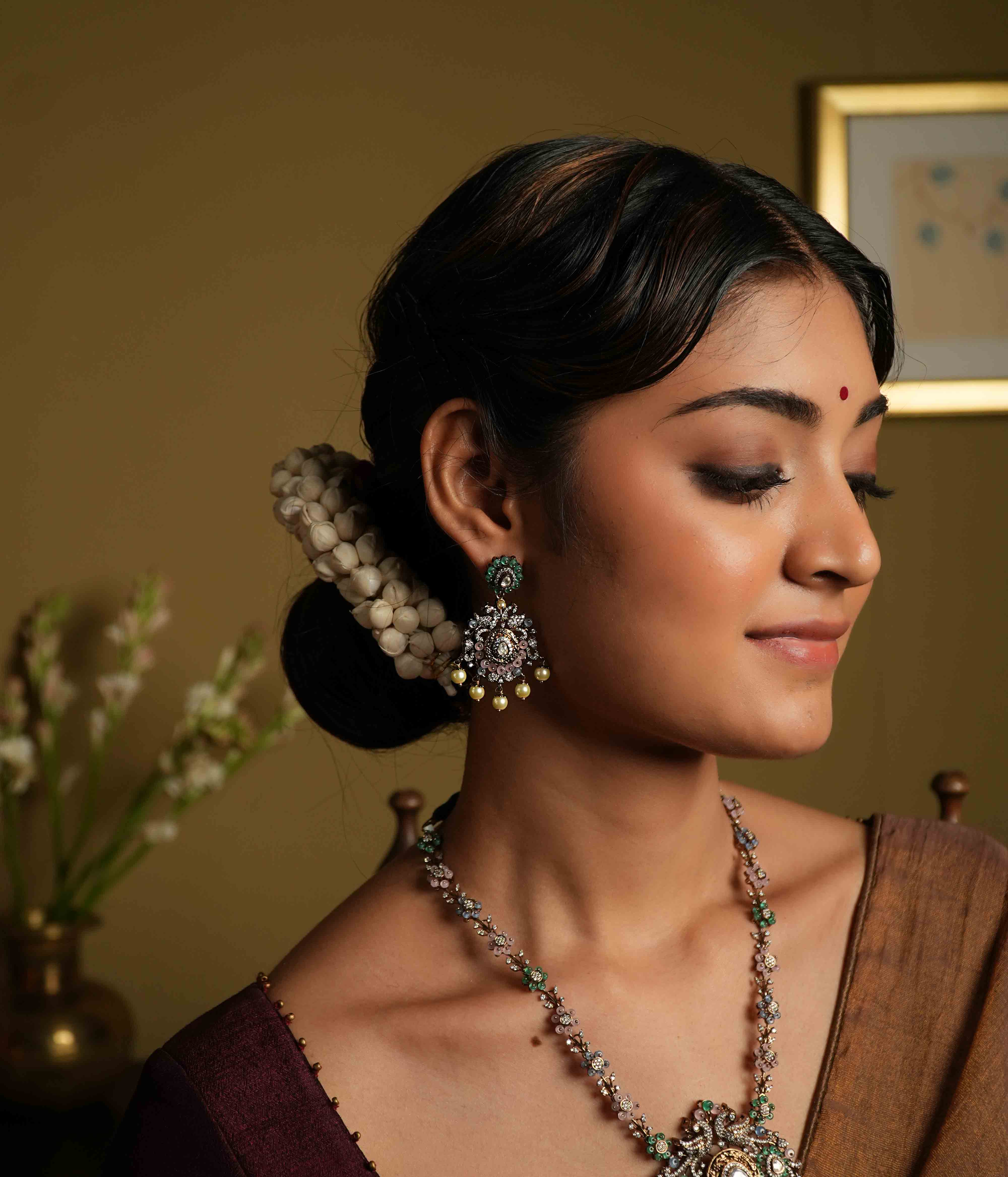 These intricate floral Chandbali earrings, crafted from 92.5 sterling silver and featuring Bombay screw fastenings, showcase moissanite and green gemstones, with show-stopping double peacock moissanite set danglings, elevating the piece to new heights of glamour and refinement.