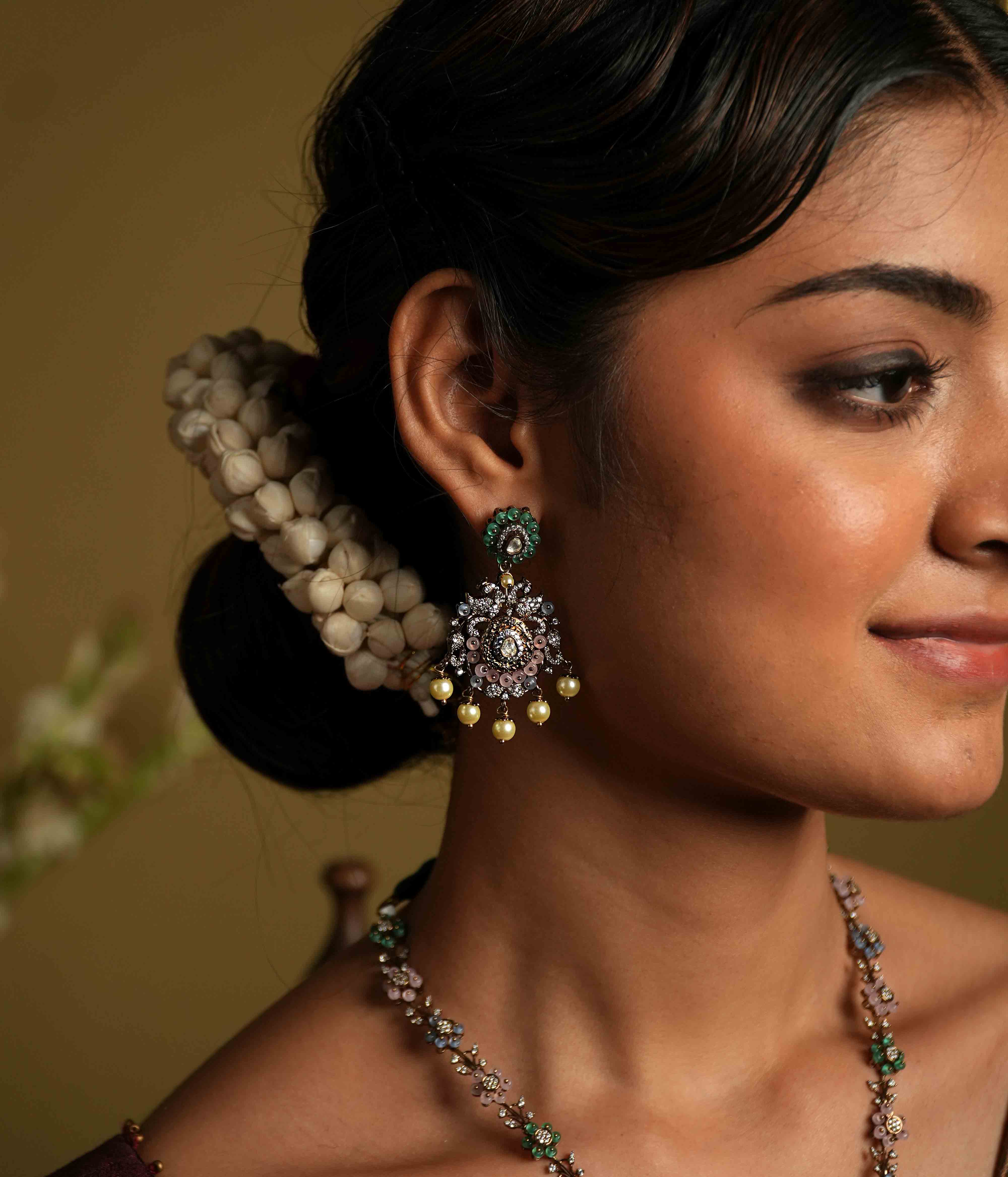 These intricate floral Chandbali earrings, crafted from 92.5 sterling silver and featuring Bombay screw fastenings, showcase moissanite and green gemstones, with show-stopping double peacock moissanite set danglings, elevating the piece to new heights of glamour and refinement.