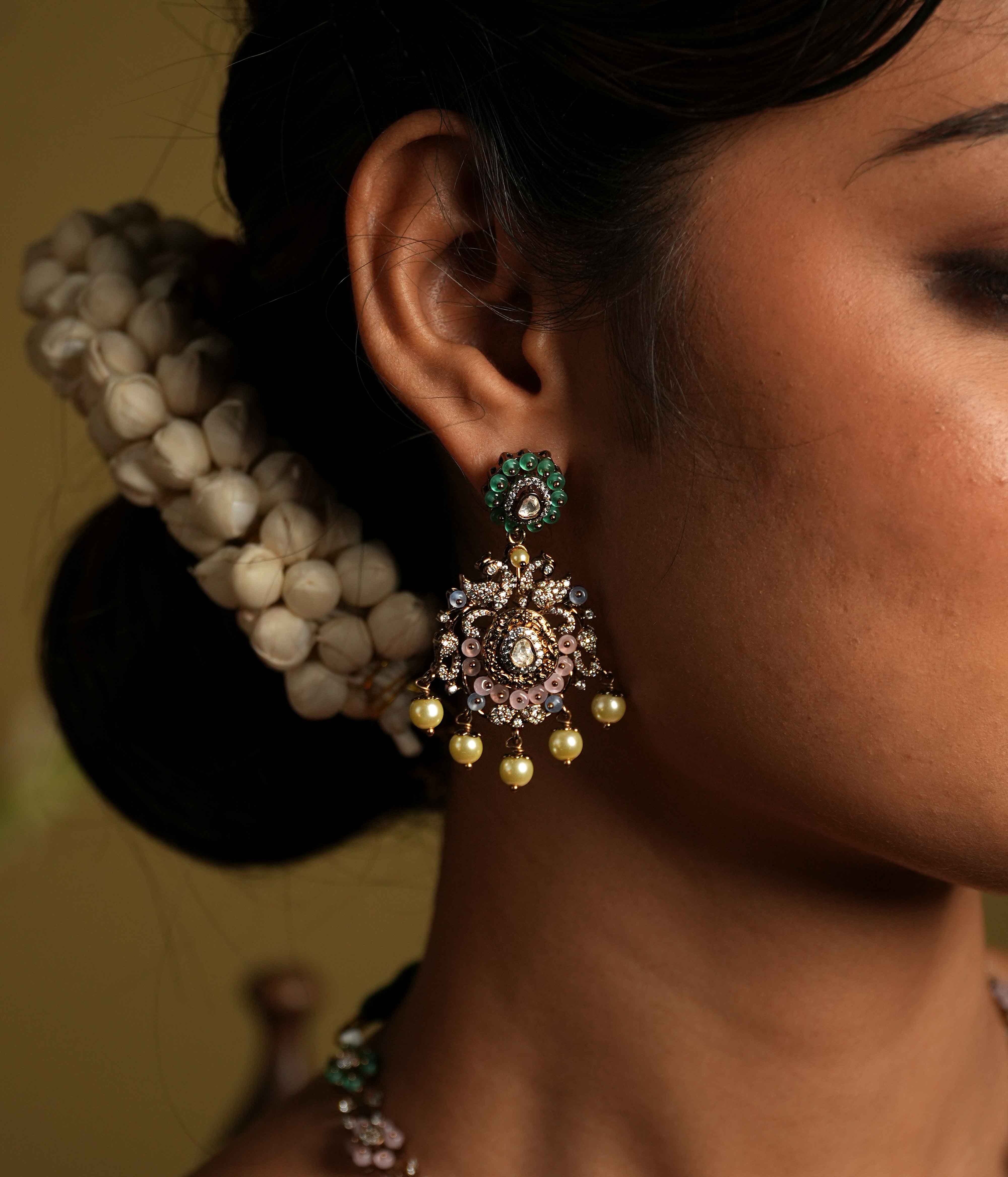 These intricate floral Chandbali earrings, crafted from 92.5 sterling silver and featuring Bombay screw fastenings, showcase moissanite and green gemstones, with show-stopping double peacock moissanite set danglings, elevating the piece to new heights of glamour and refinement.
