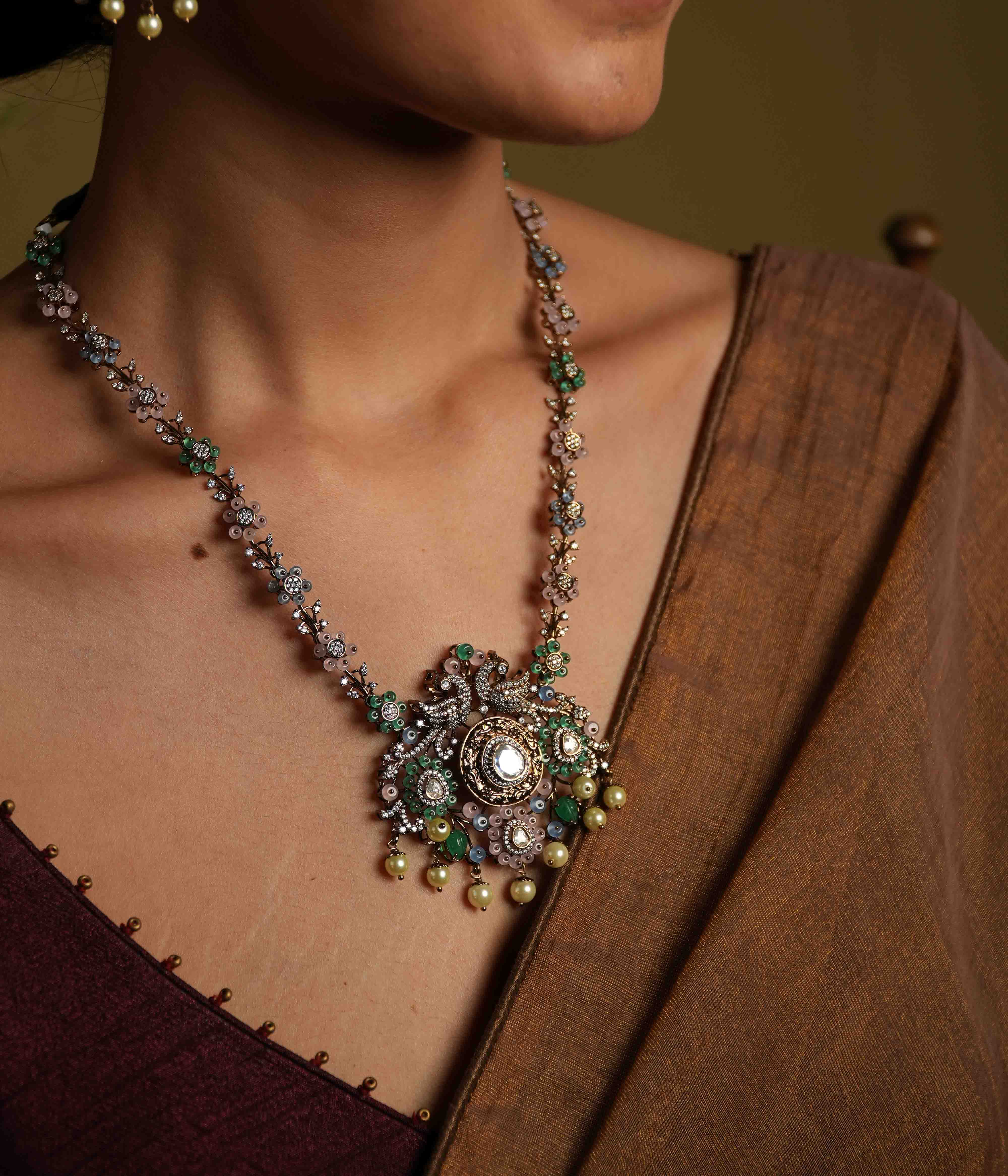 A handcrafted 92.5 sterling silver and 14ct dark antique gold-plated necklace, featuring CZ stones, polki stones, green beads, and pearls in a Victorian finish, showcasing intricate floral designs and a show-stopping double peacock moissanite pendant.