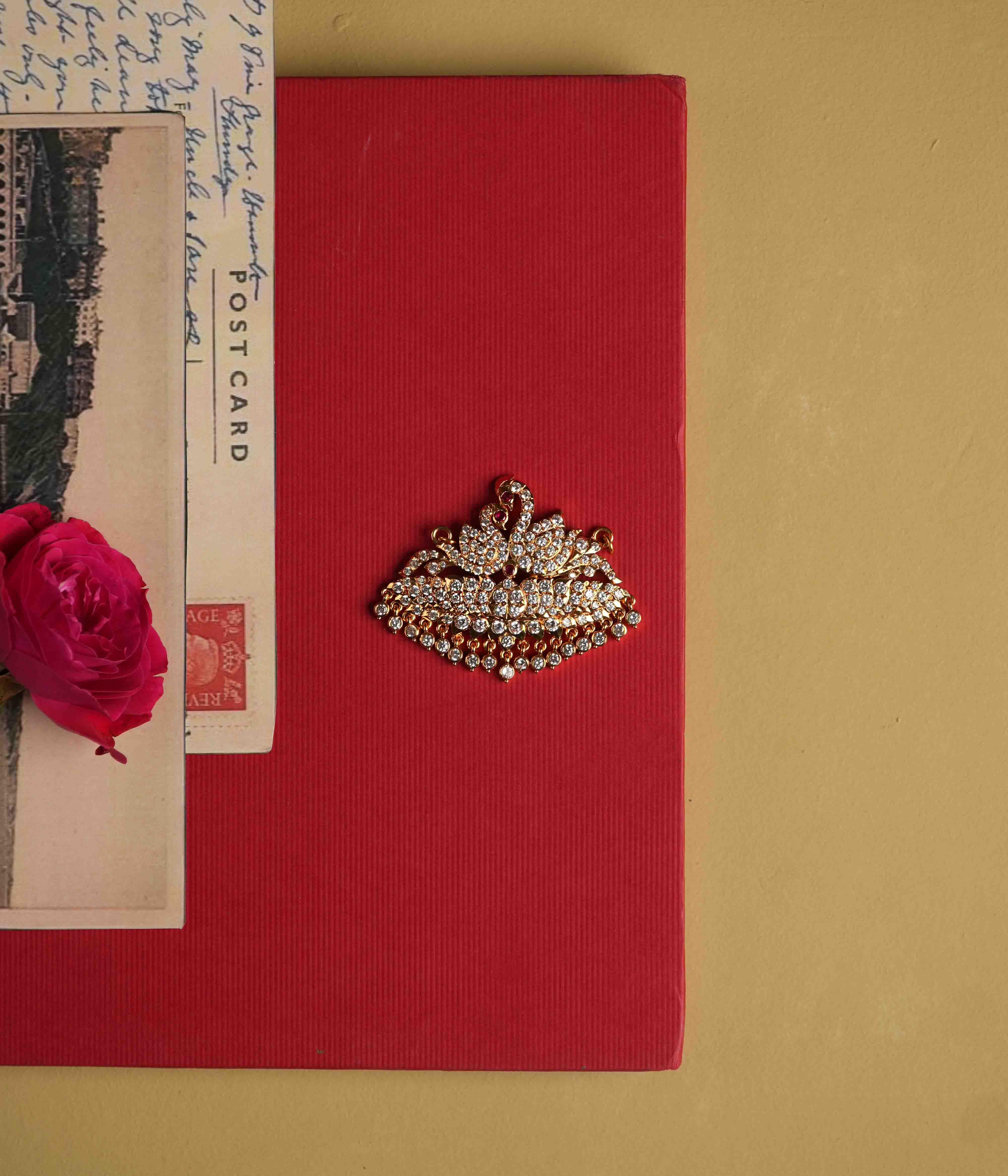 Crafted from 92.5 sterling silver, this majestic pendant showcases a double swan design inspired by Chettinad artistry. A vibrant red spinel and sparkling CZ stones add a touch of regal elegance, while a discreet single hook on the back allows for easy chain insertion.