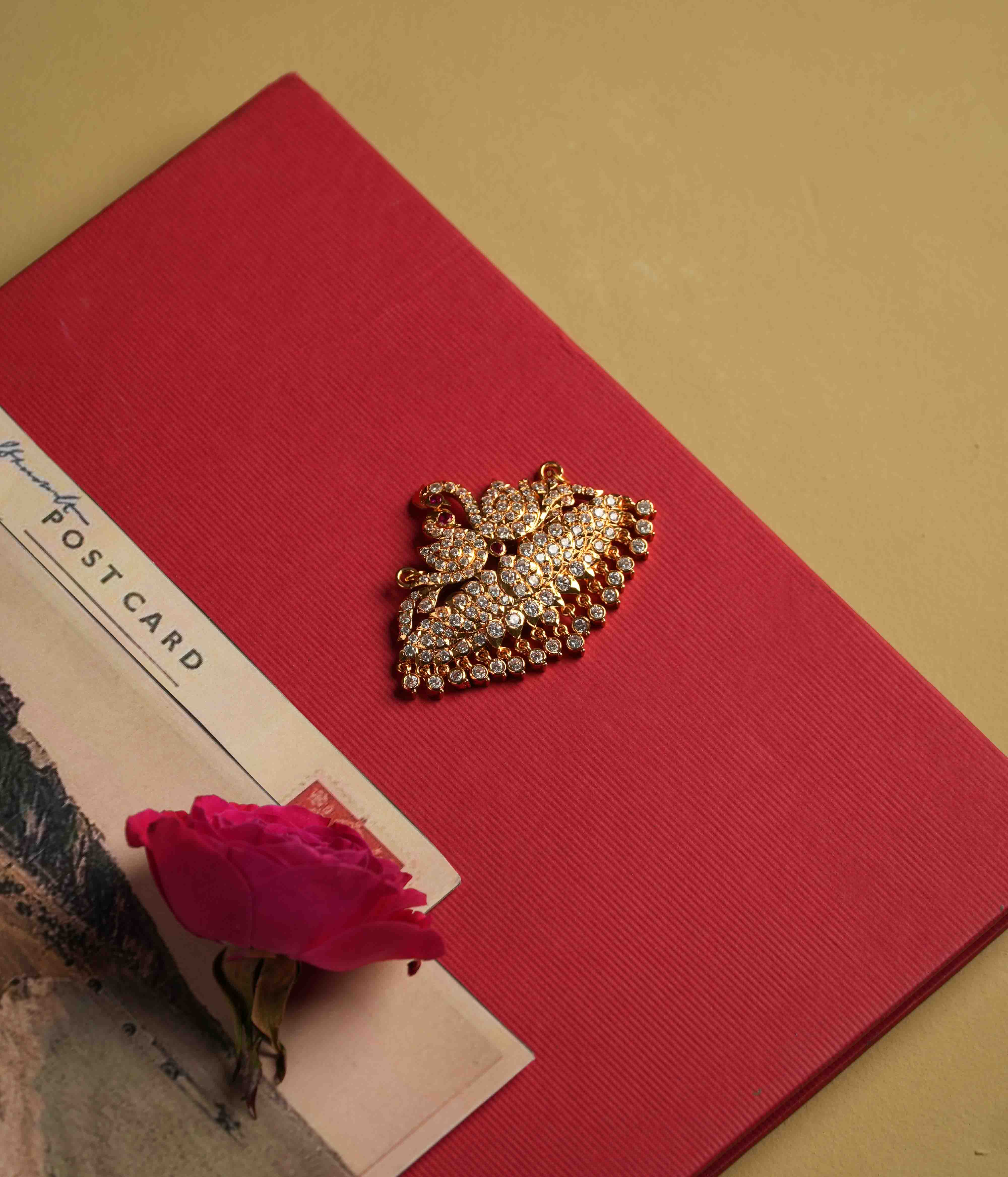 Crafted from 92.5 sterling silver, this majestic pendant showcases a double swan design inspired by Chettinad artistry. A vibrant red spinel and sparkling CZ stones add a touch of regal elegance, while a discreet single hook on the back allows for easy chain insertion.