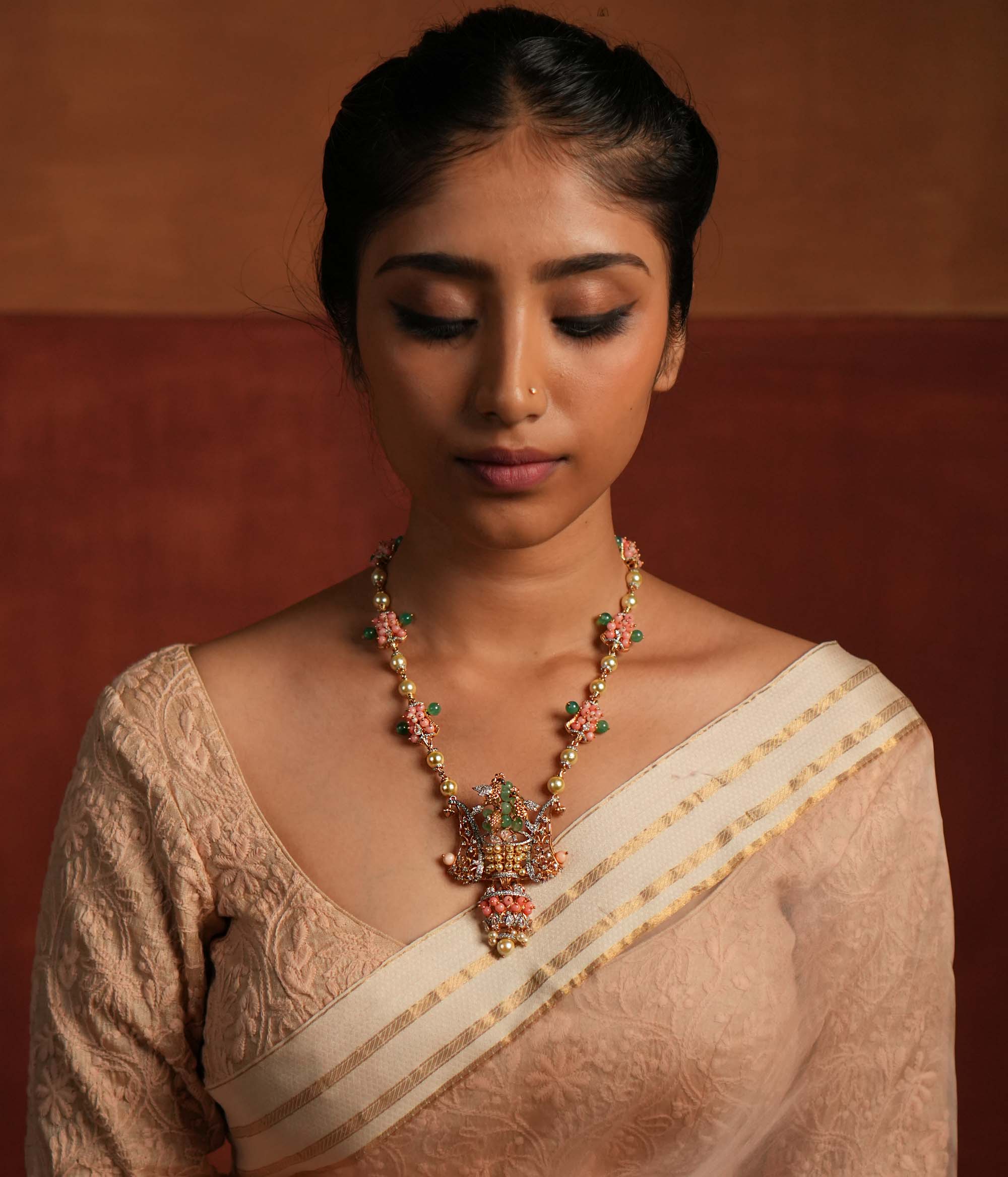 A gold-plated silver necklace adorned with Moissanite Polki stones, Swarovski crystals, green gemstones, coral beads, freshwater pearls, and green strawberry quartz beads. The intricate pendant showcases exquisite craftsmanship, blending traditional and contemporary design elements for a statement look.