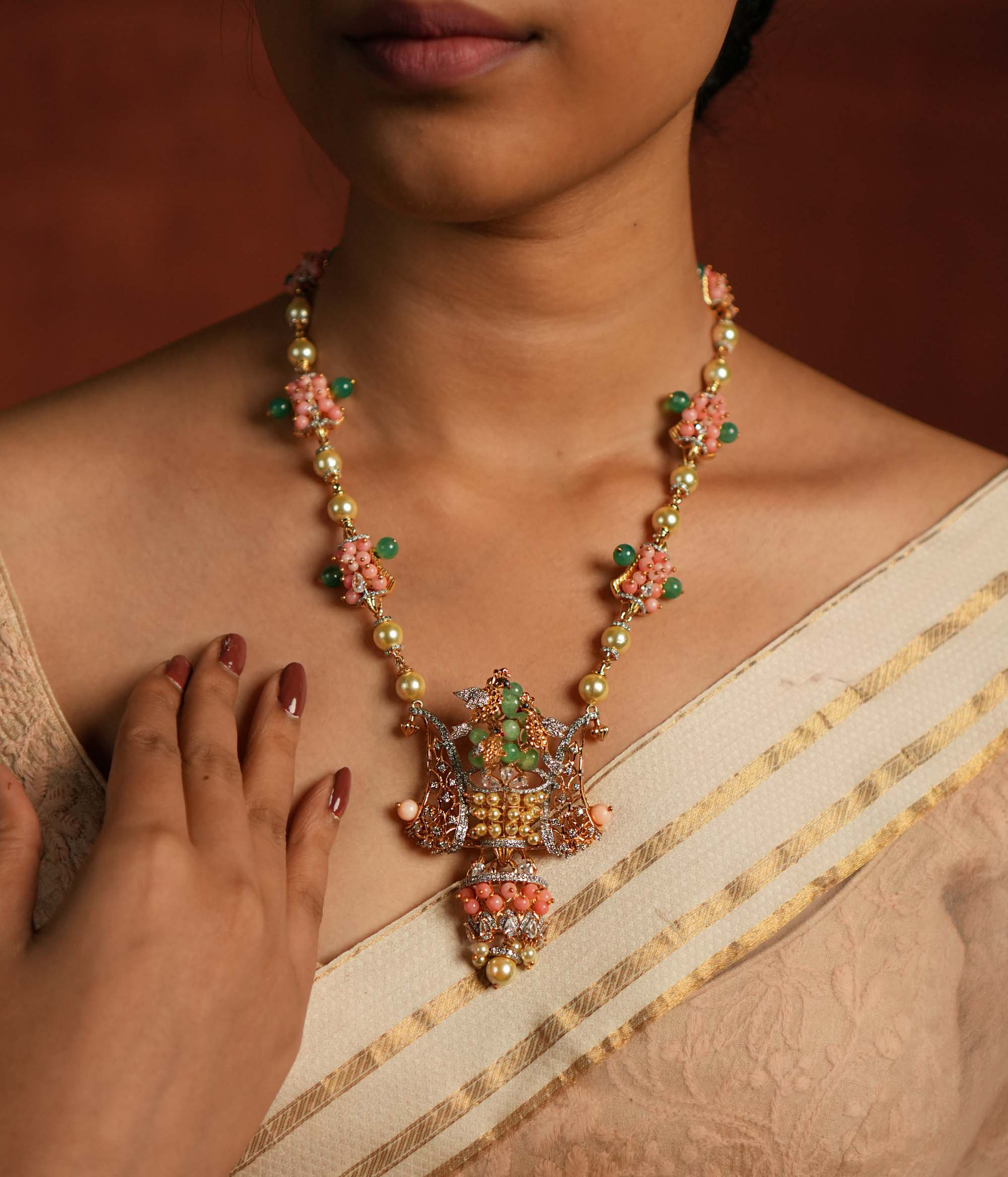 A gold-plated silver necklace adorned with Moissanite Polki stones, Swarovski crystals, green gemstones, coral beads, freshwater pearls, and green strawberry quartz beads. The intricate pendant showcases exquisite craftsmanship, blending traditional and contemporary design elements for a statement look.