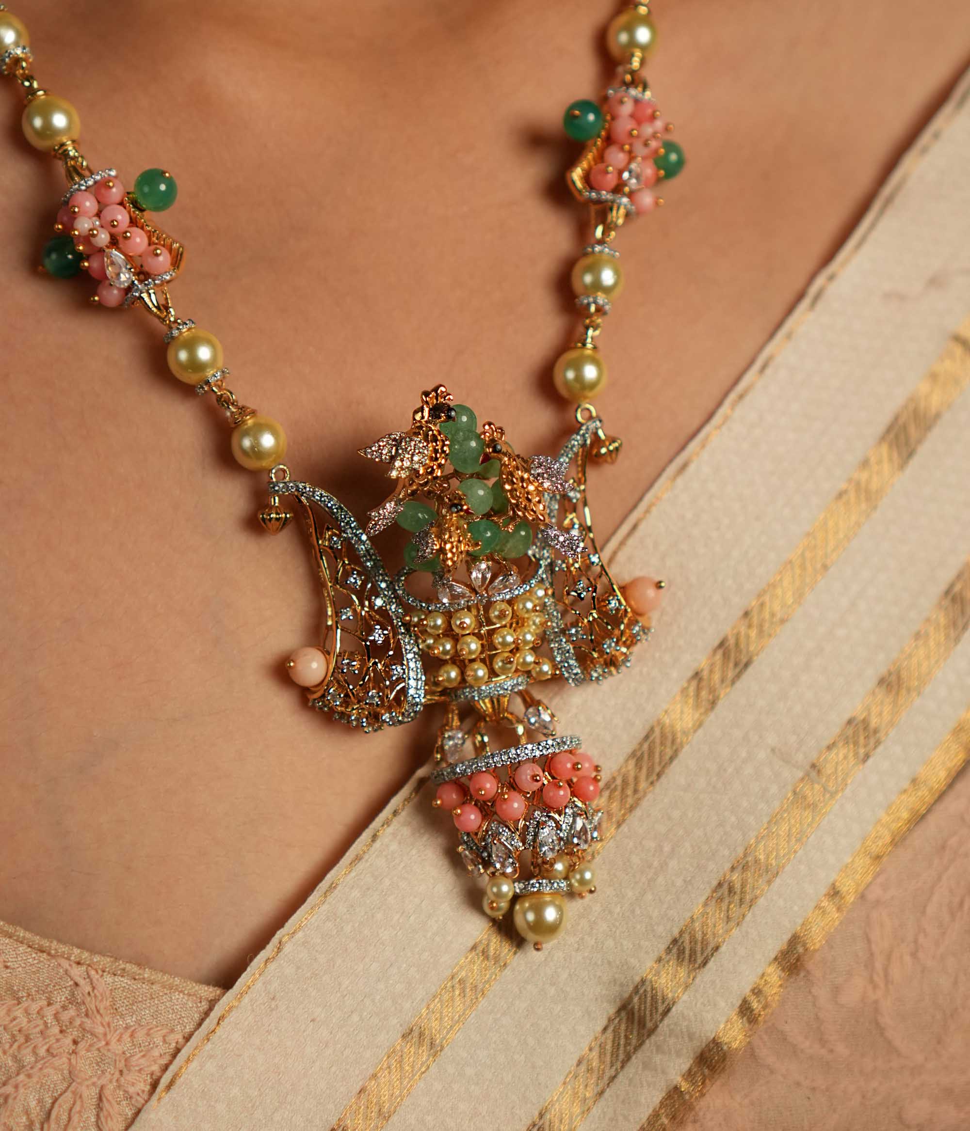 A gold-plated silver necklace adorned with Moissanite Polki stones, Swarovski crystals, green gemstones, coral beads, freshwater pearls, and green strawberry quartz beads. The intricate pendant showcases exquisite craftsmanship, blending traditional and contemporary design elements for a statement look.