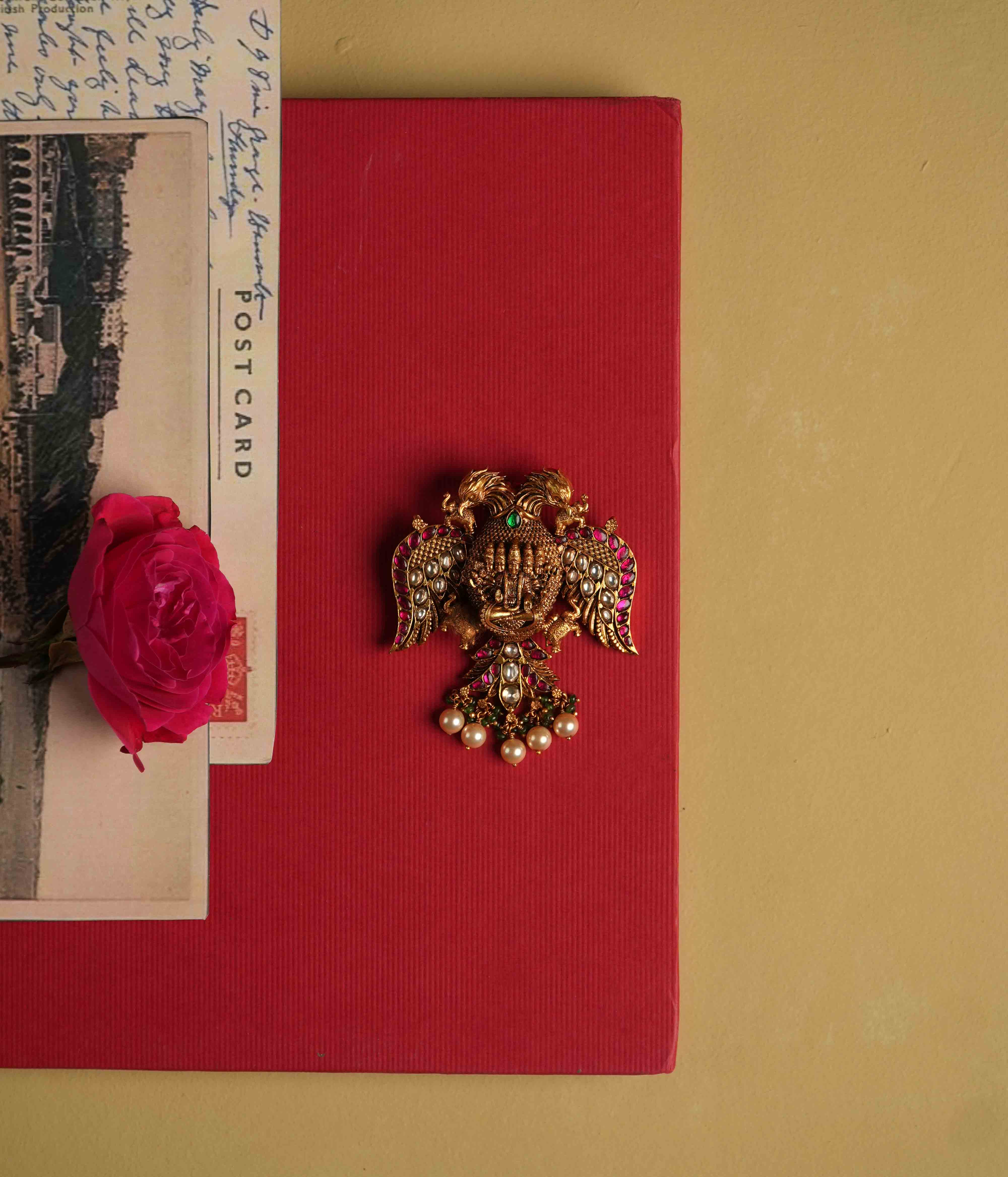 Antique gold-plated 92.5 sterling silver pendant featuring intricate deity and double eagle engravings, adorned with red and white Kundan stones, green beads, and pearls. A timeless heirloom radiating temple-inspired grandeur and divine opulence.