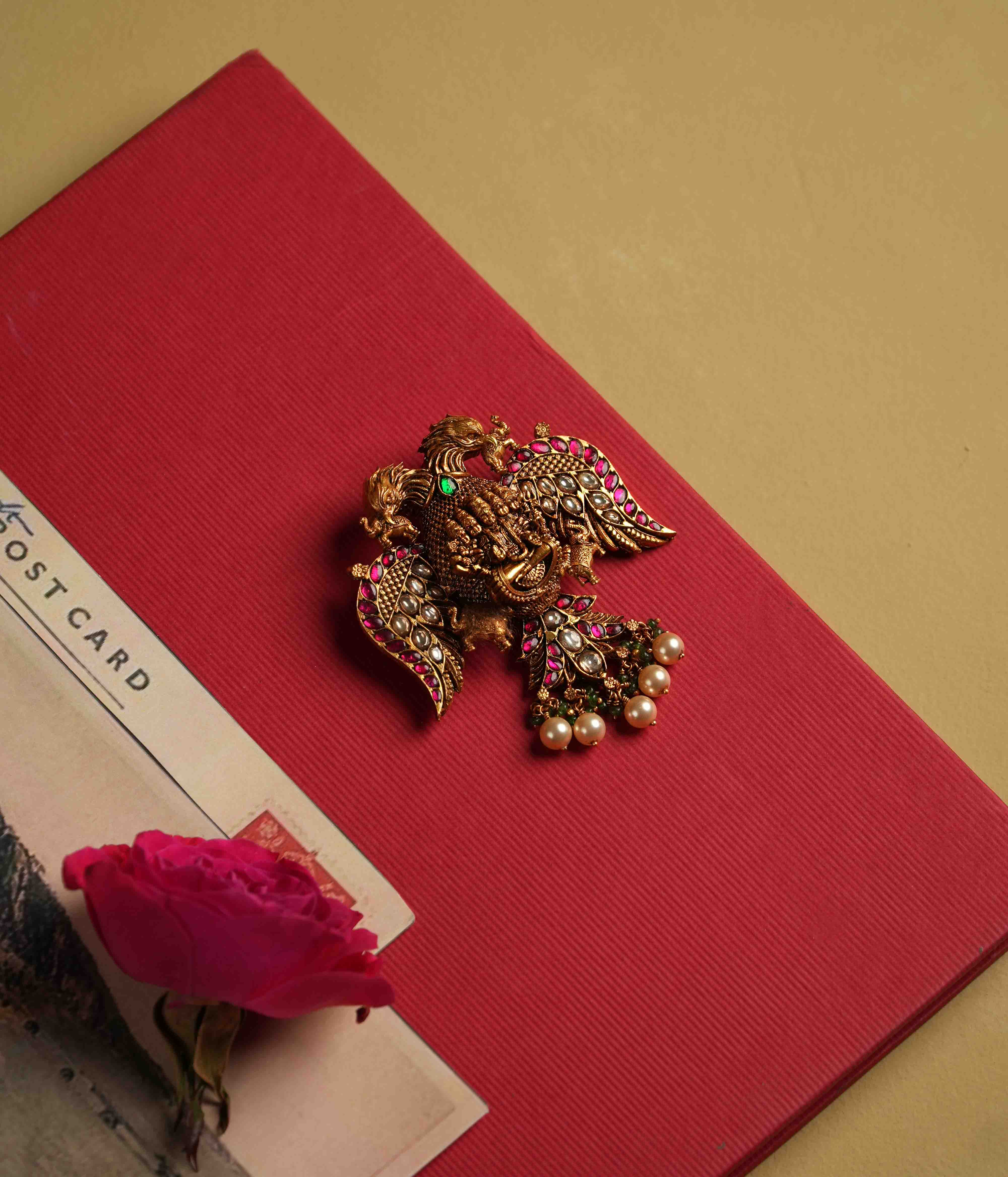 Antique gold-plated 92.5 sterling silver pendant featuring intricate deity and double eagle engravings, adorned with red and white Kundan stones, green beads, and pearls. A timeless heirloom radiating temple-inspired grandeur and divine opulence.