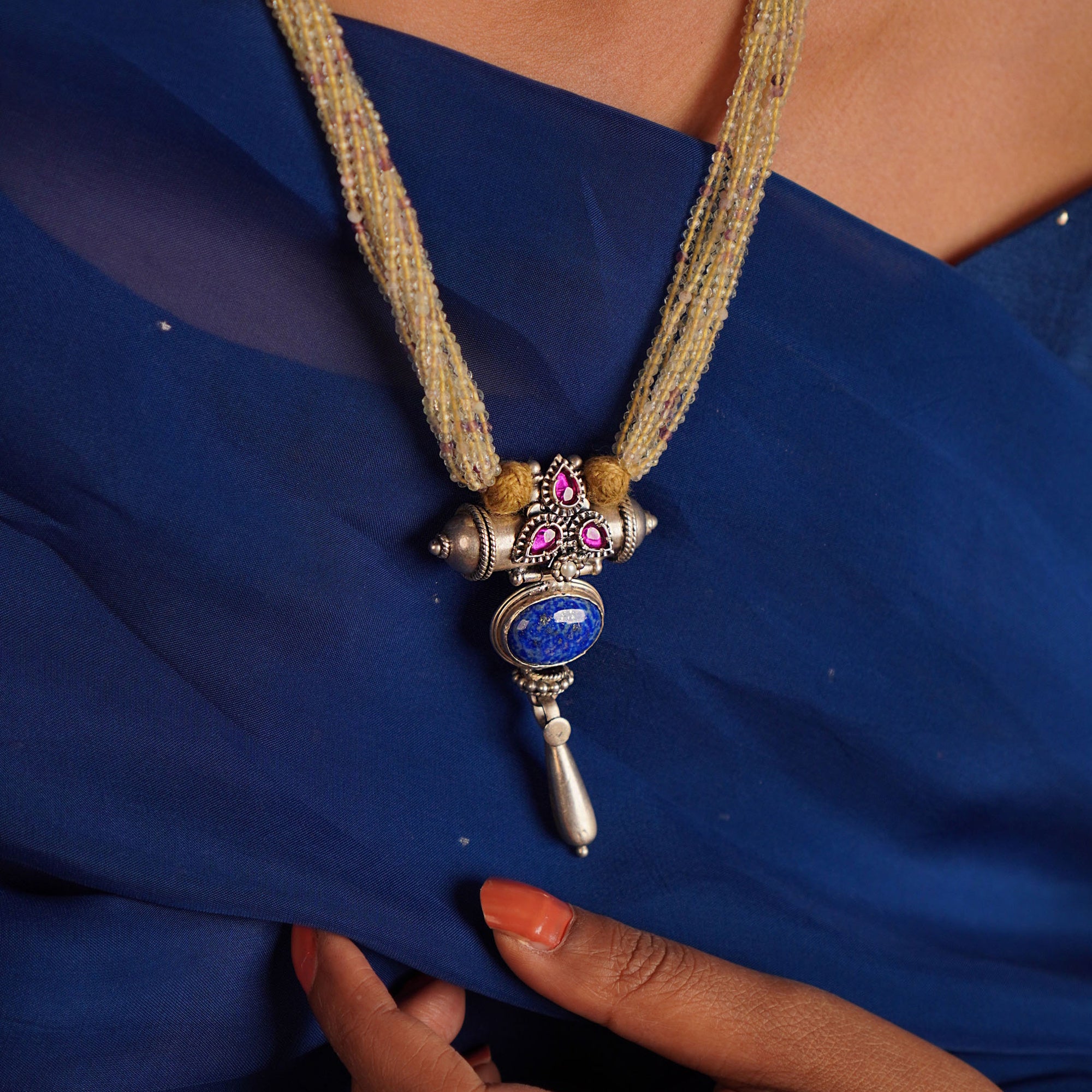 Decorative necklace with a blue pendant on a blue fabric background