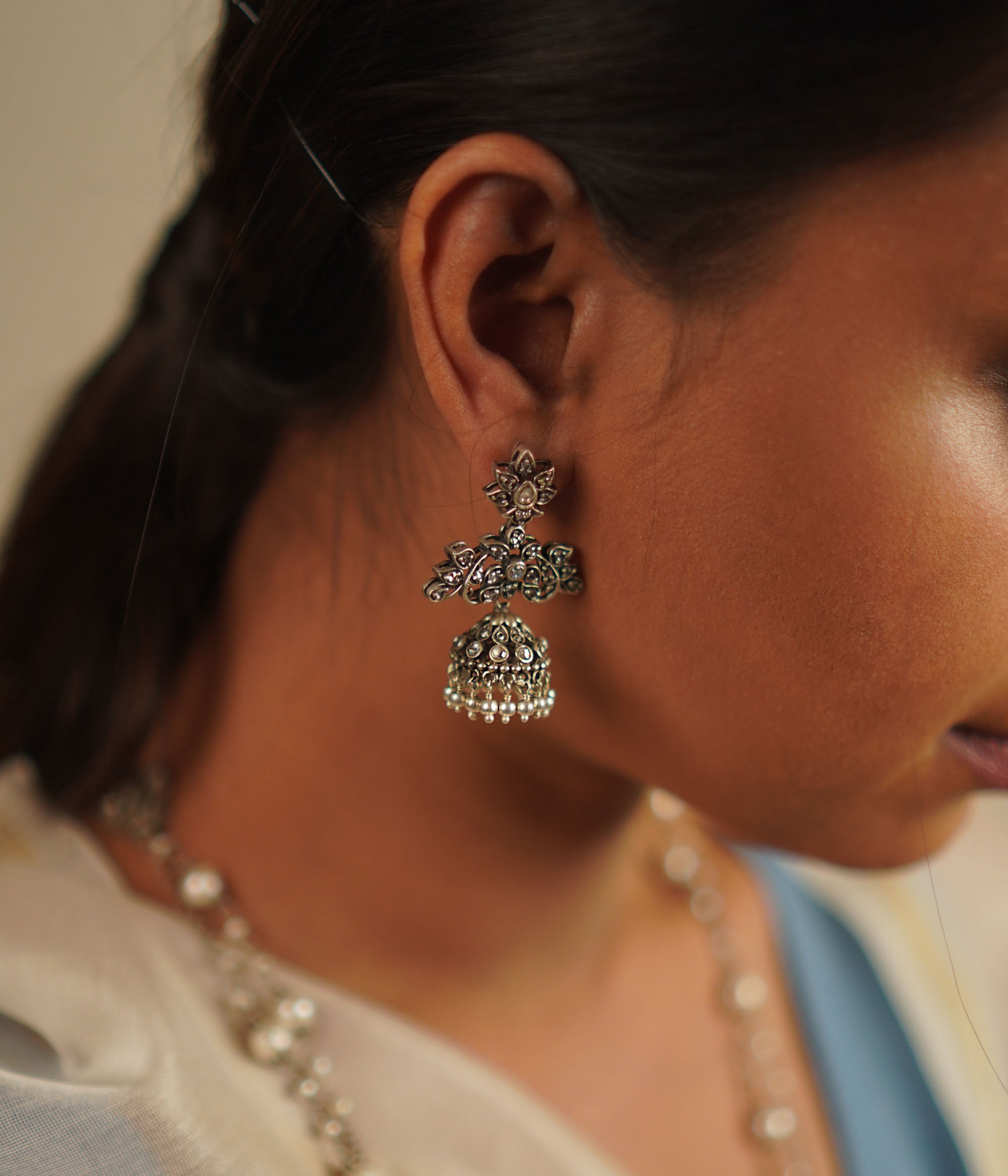 The Heti earrings, meticulously handcrafted in oxidized silver, showcase intricate detailing that reflects the essence of Indian heritage. Embellished with radiant white kundan stones, these jhumkas seamlessly blend tradition with contemporary elegance.