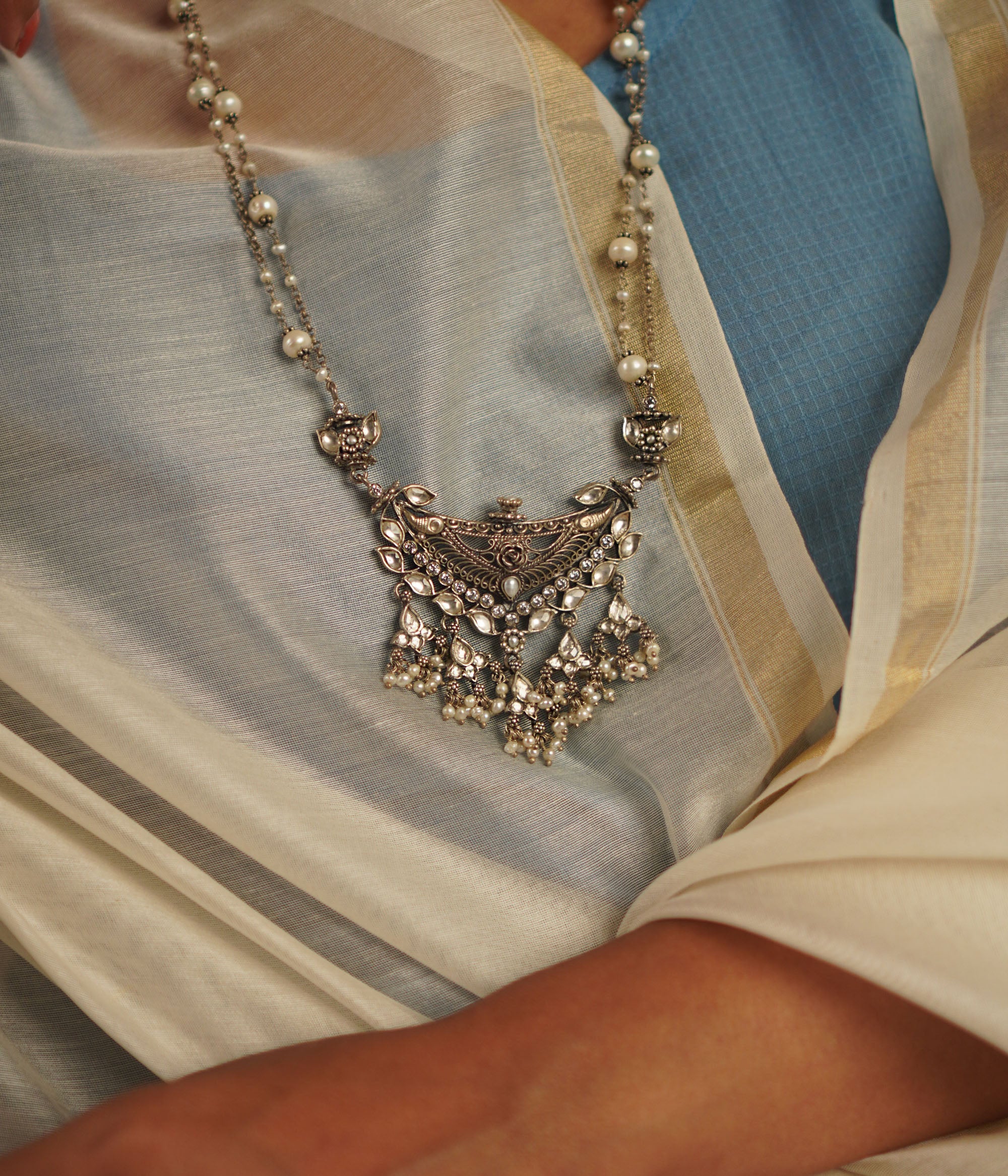 This oxidized silver necklace, adorned with luminous white kundan stones and delicate pearls, exudes an air of vintage sophistication. A perfect harmony of tradition and elegance, it’s a timeless statement piece.