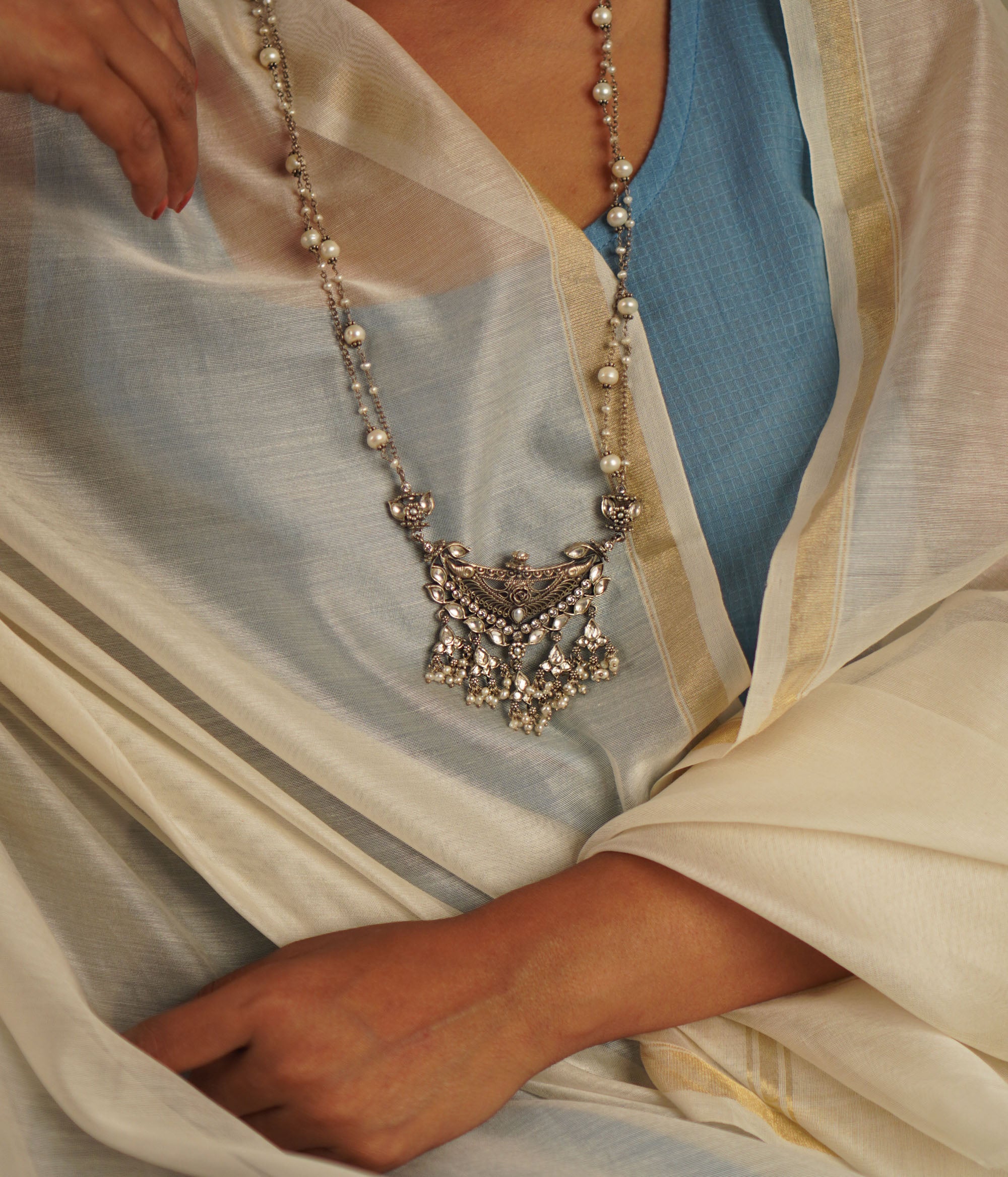 This oxidized silver necklace, adorned with luminous white kundan stones and delicate pearls, exudes an air of vintage sophistication. A perfect harmony of tradition and elegance, it’s a timeless statement piece.
