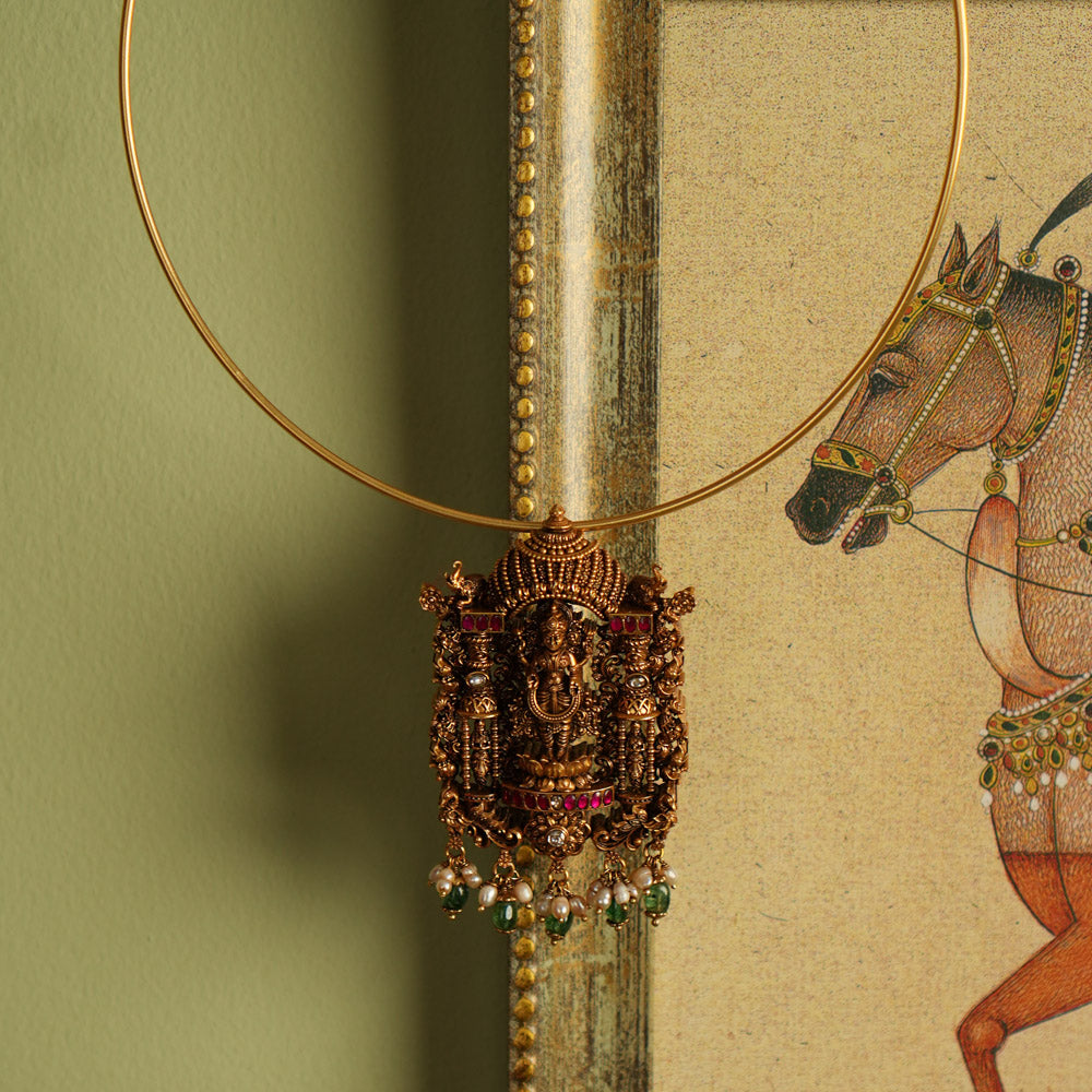 Exquisite gold-plated silver temple jewelry pendant featuring a beautifully crafted Lord Lakshmi motif at the center. Adorned with radiant red and white Kundan stones, elegant green beads, and delicate pearl drops, this pendant offers both single and double hooks for versatile styling, making it a perfect blend of tradition and elegance.
