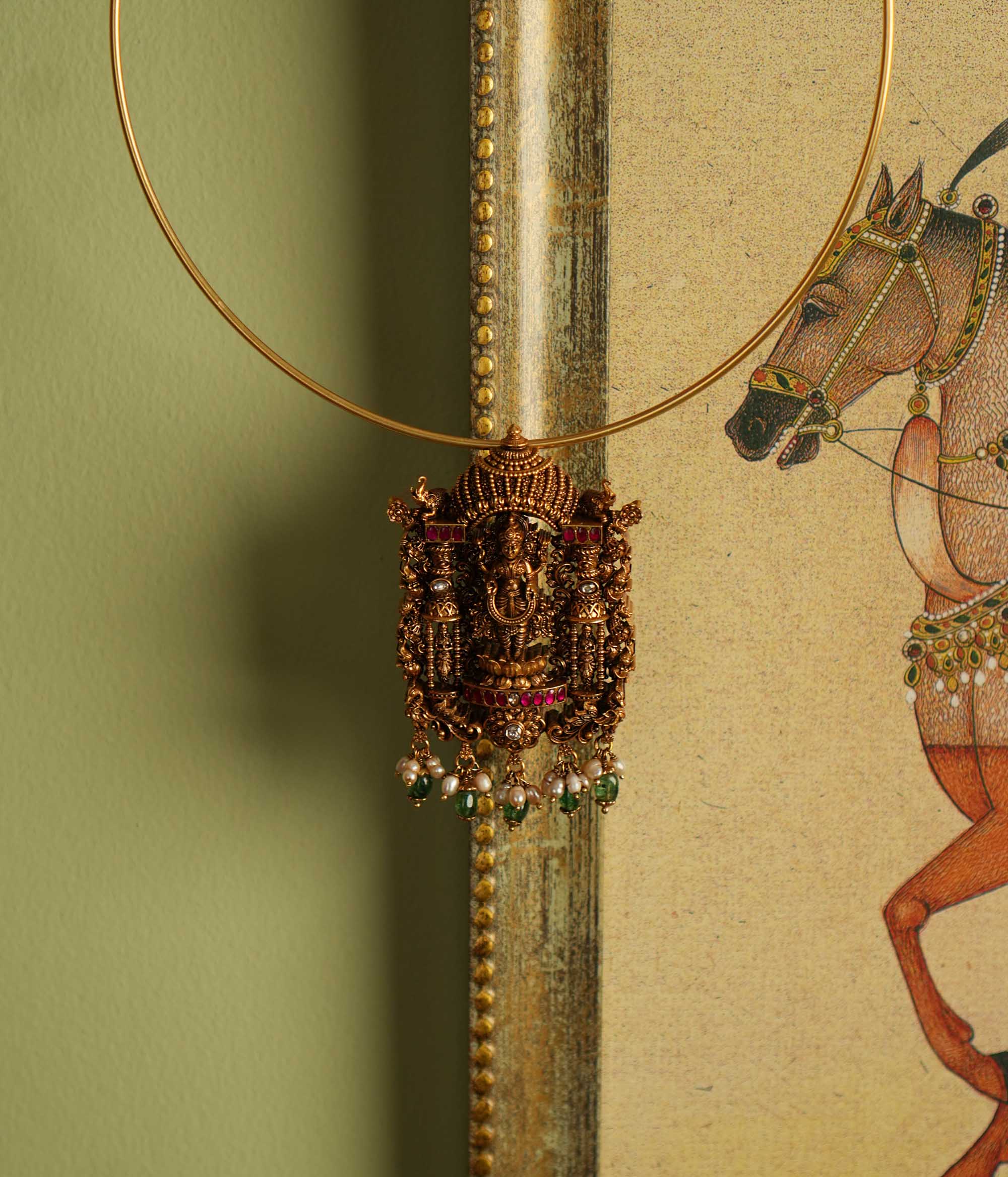 Exquisite gold-plated silver temple jewelry pendant featuring a beautifully crafted Lord Lakshmi motif at the center. Adorned with radiant red and white Kundan stones, elegant green beads, and delicate pearl drops, this pendant offers both single and double hooks for versatile styling, making it a perfect blend of tradition and elegance.