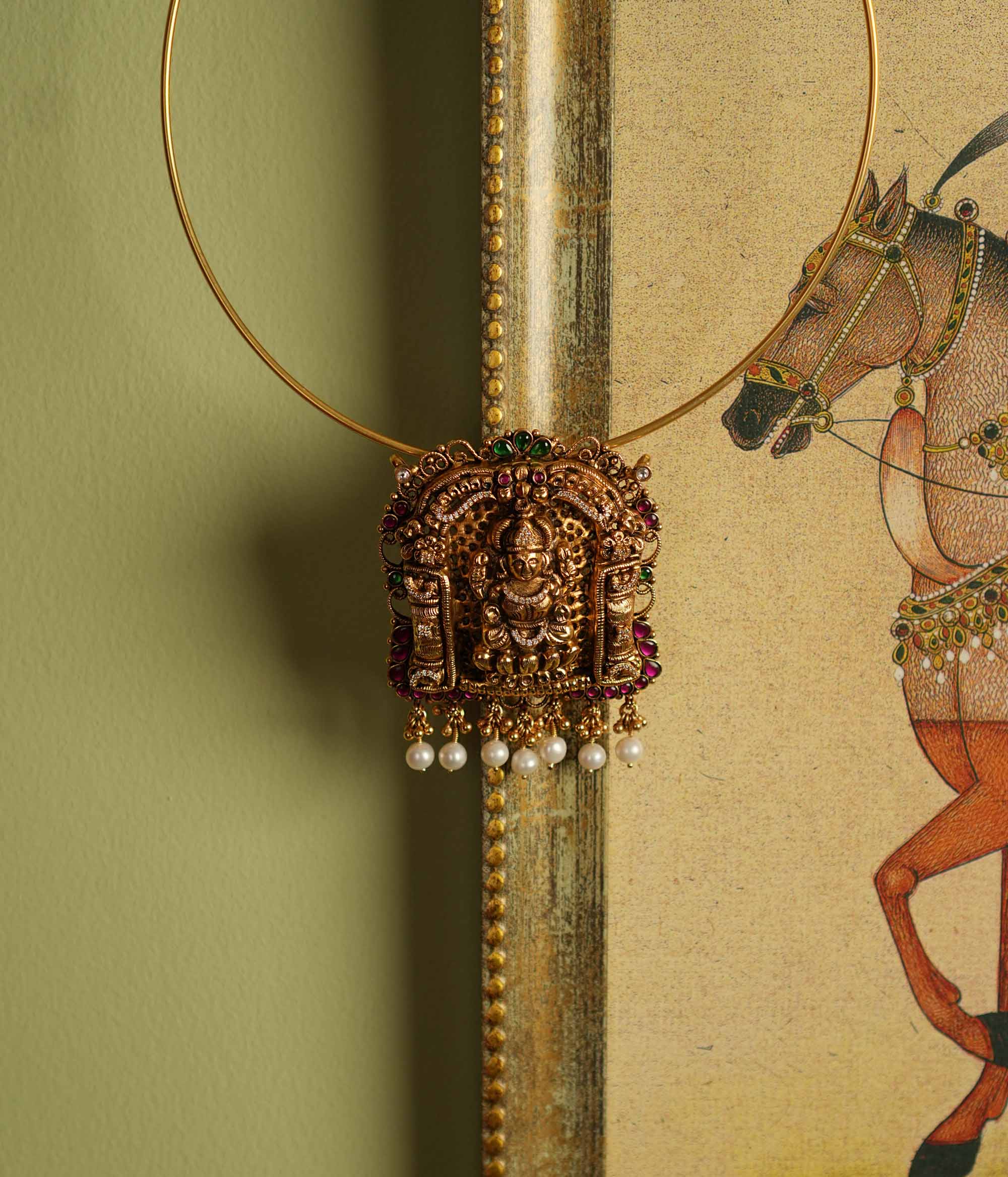 Traditional gold-plated silver temple jewelry pendant featuring Goddess Lakshmi at the center, adorned with radiant red and green Kundan stones and elegant pearl drops. Designed with both single and double hooks for versatile styling, this pendant exudes divine grace and timeless craftsmanship.