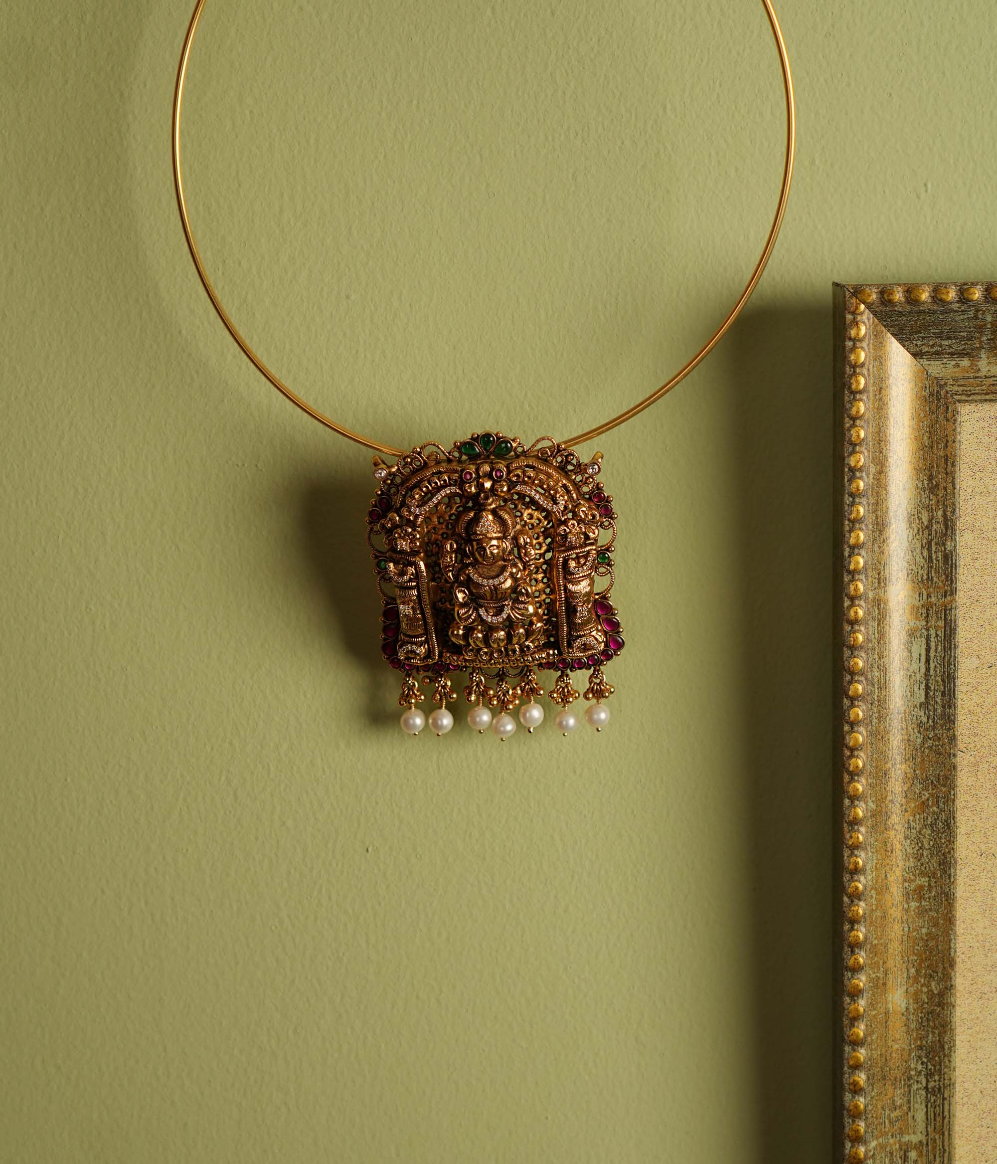 Traditional gold-plated silver temple jewelry pendant featuring Goddess Lakshmi at the center, adorned with radiant red and green Kundan stones and elegant pearl drops. Designed with both single and double hooks for versatile styling, this pendant exudes divine grace and timeless craftsmanship.