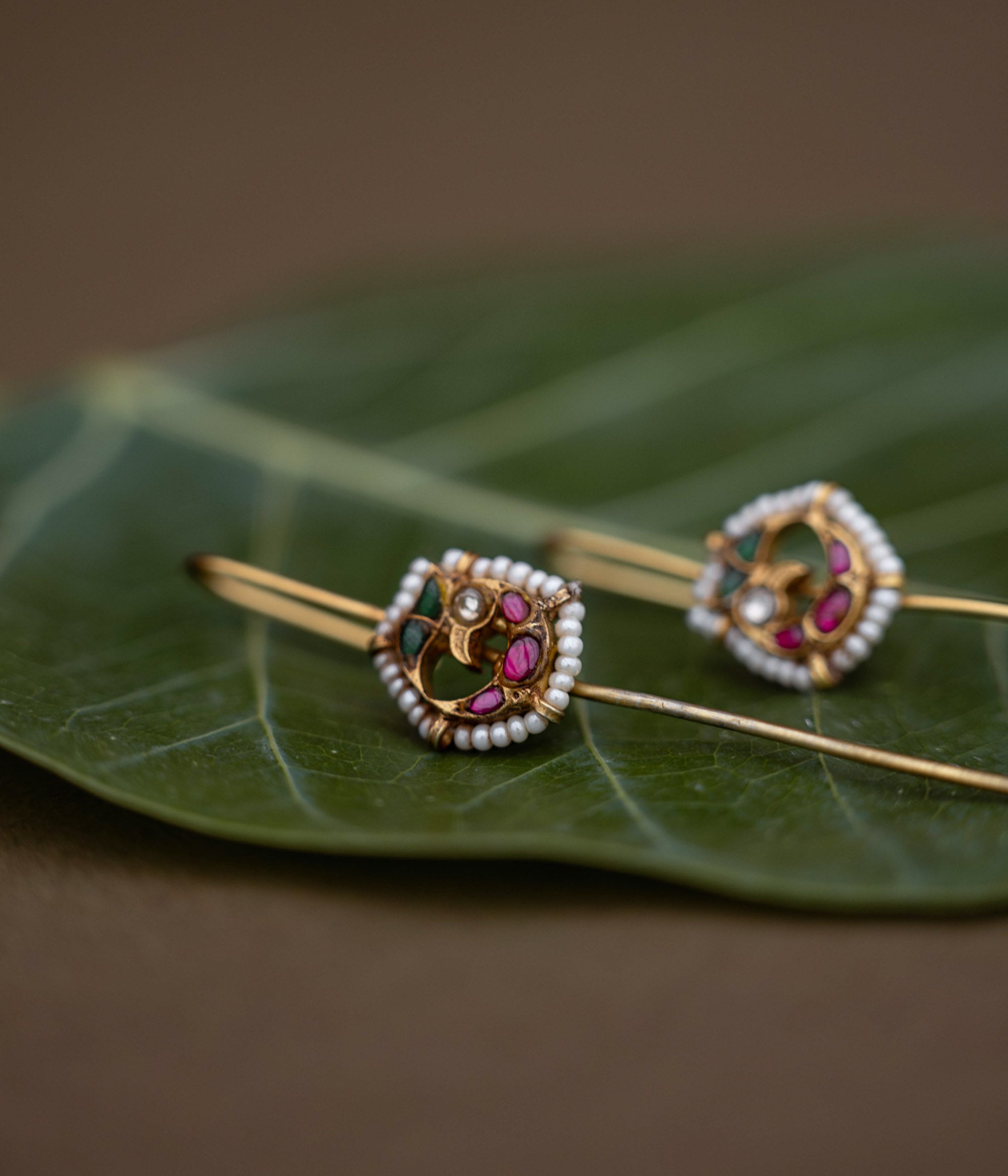 A handcrafted 92.5 sterling silver and 22ct gold-plated bugadi, featuring white, red, and green Kundan stones and pearls, with intricate goldwork and a delicate pearl border, embodying heritage, grace, and divine beauty.