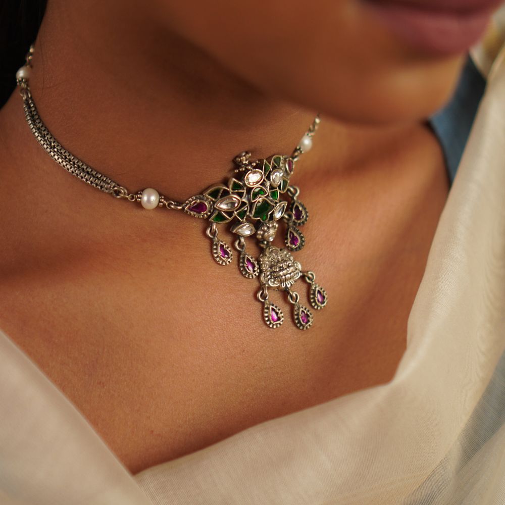 This oxidized silver choker, embellished with radiant kundan stones and delicate pearls, captures the essence of a treasured heirloom. A seamless fusion of heritage and charm, it embodies timeless grace with a hint of whimsy.