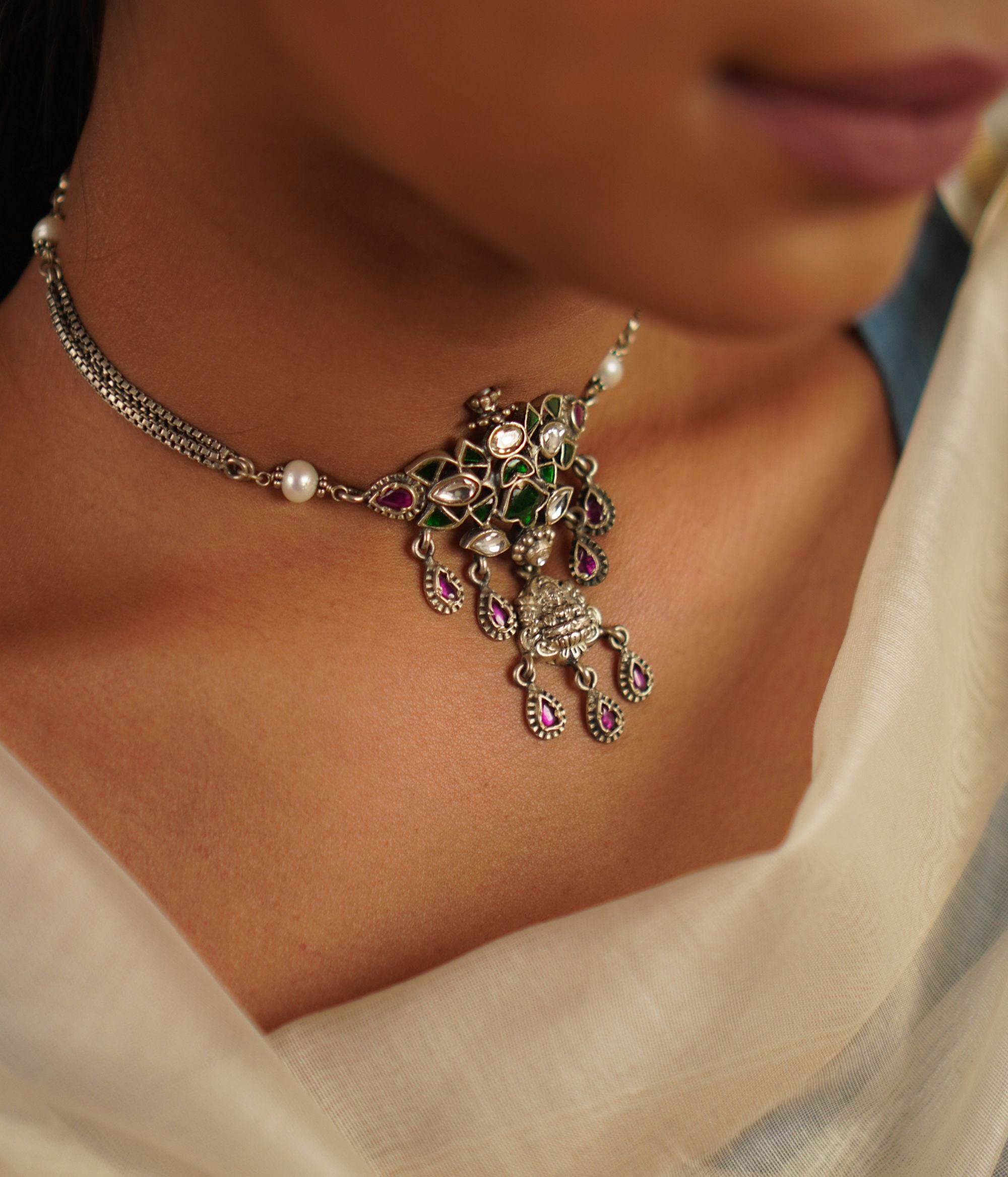 This oxidized silver choker, embellished with radiant kundan stones and delicate pearls, captures the essence of a treasured heirloom. A seamless fusion of heritage and charm, it embodies timeless grace with a hint of whimsy.