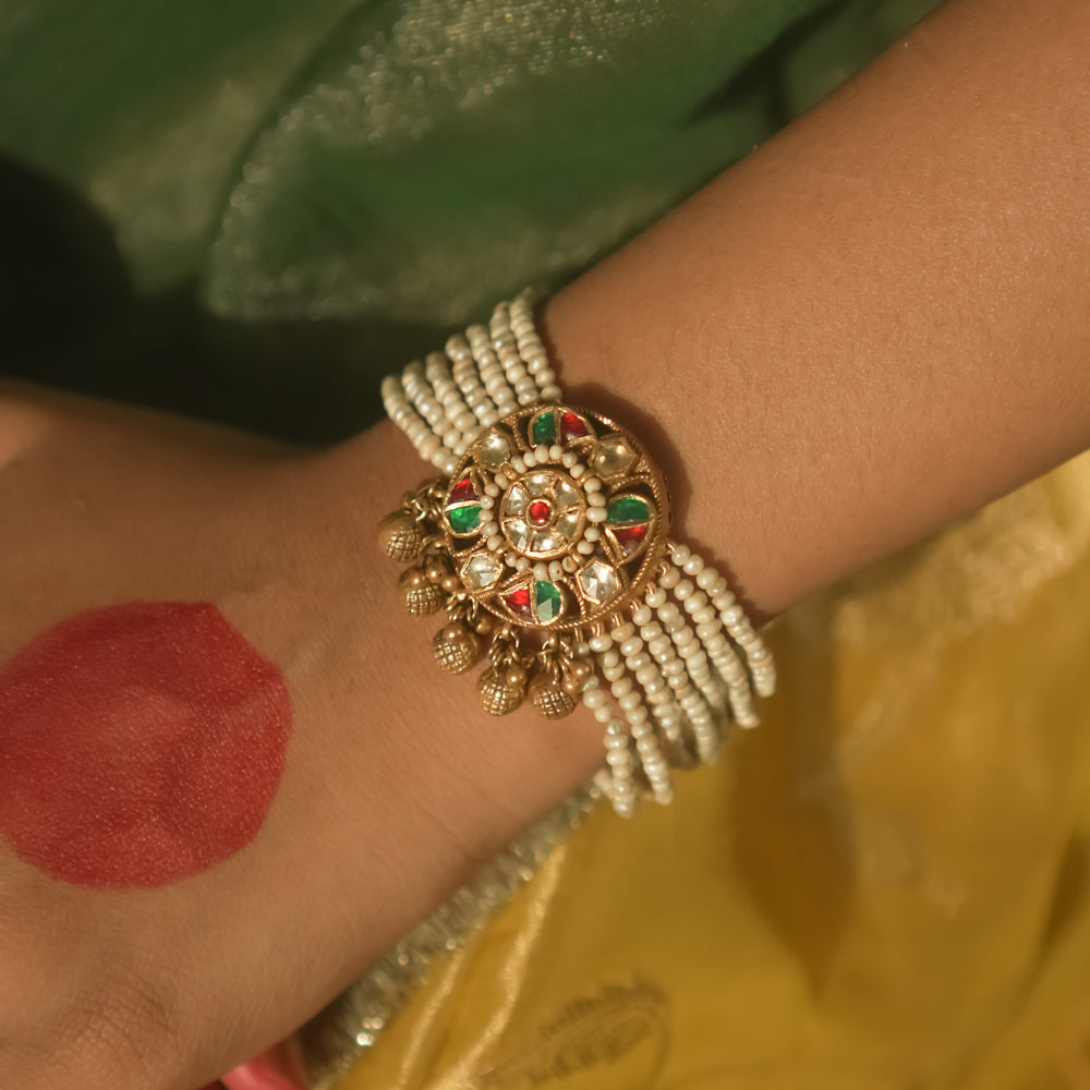 Bracelet with beaded pearls and a gold centerpiece studded with red and green Kundan.
