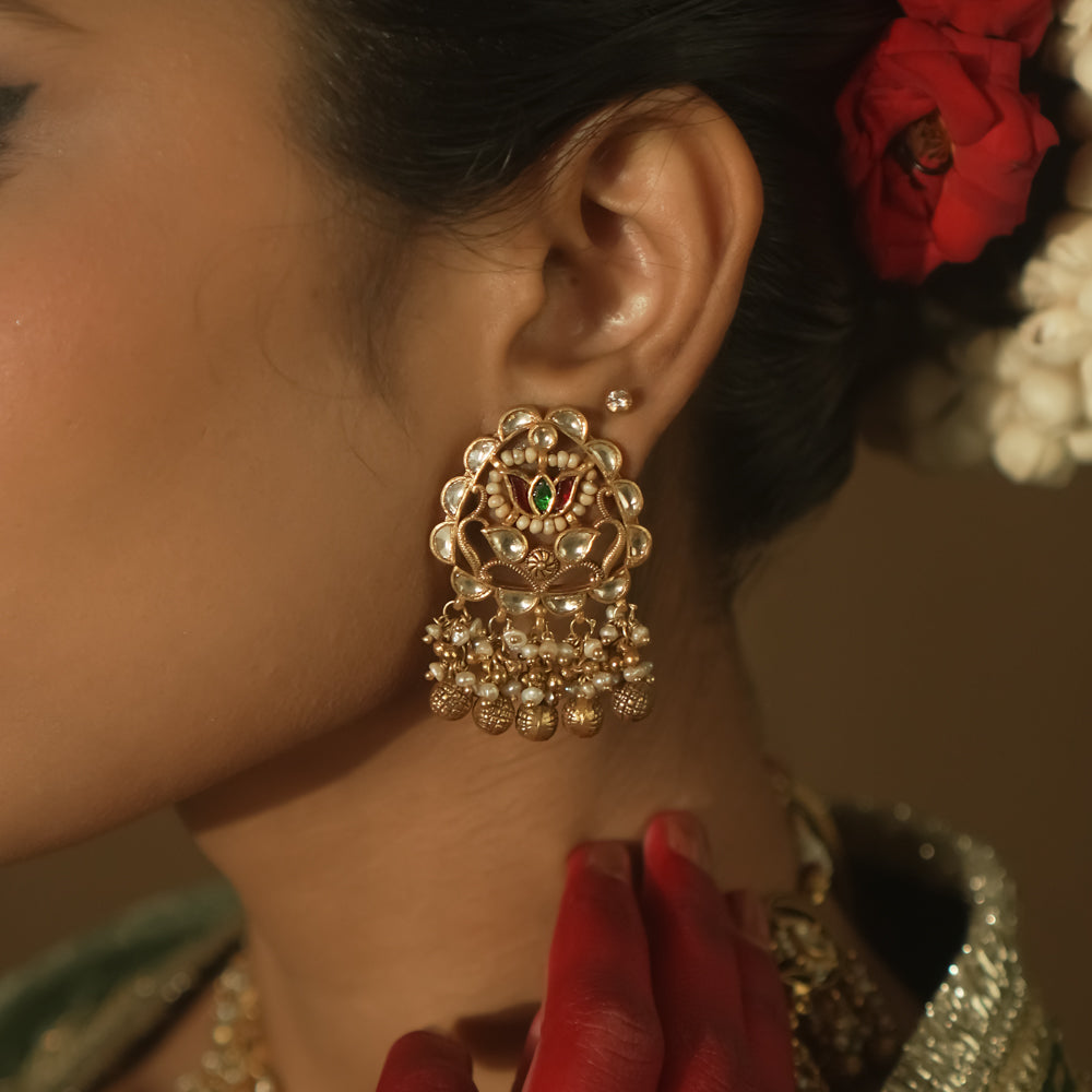 Gold-plated silver earrings with beaded tassels and a central medallion with green Kundan stones.