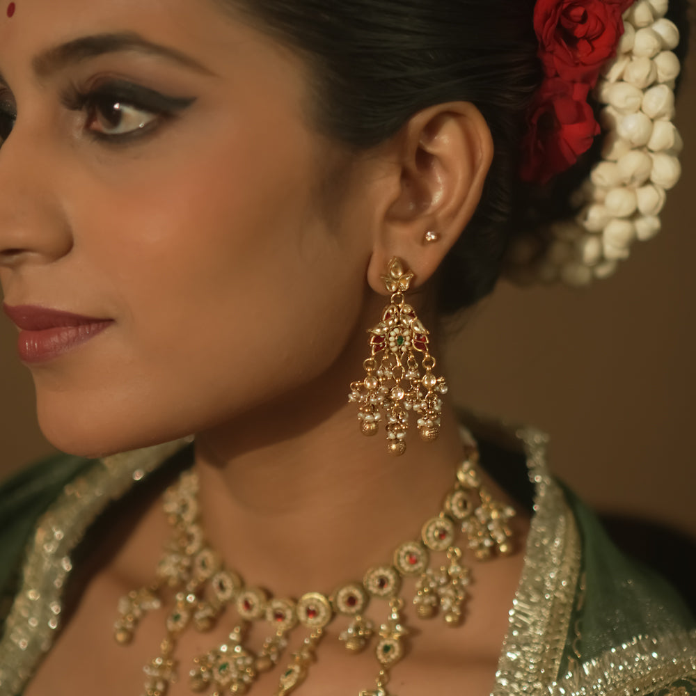 Gold-plated silver earrings with tasseled Kundan clusters, red gems, and pearls.