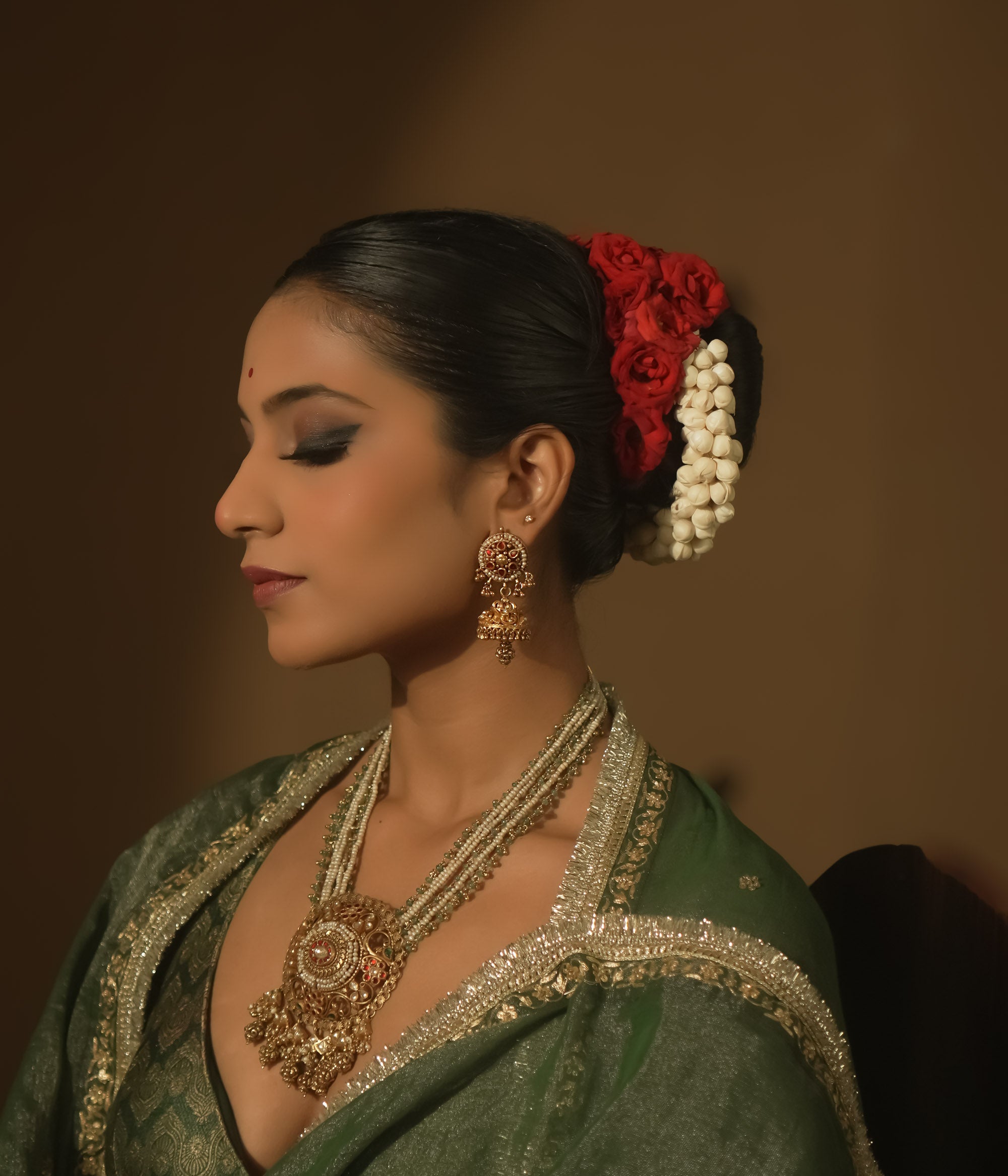 Gold earrings with intricate swirls and a central red Kundan stone.