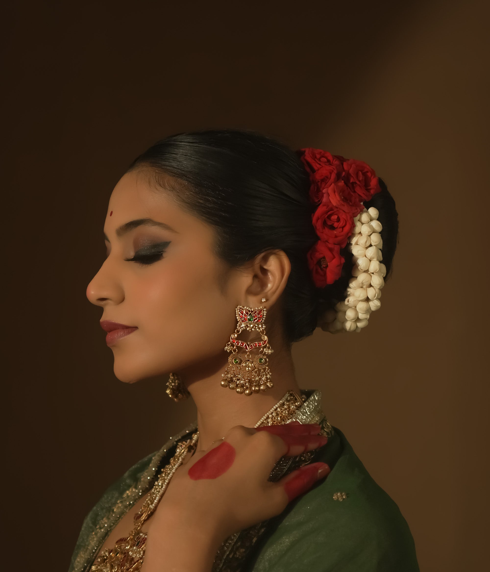 Gold earrings with red and green Kundan stones and dangling pearls.