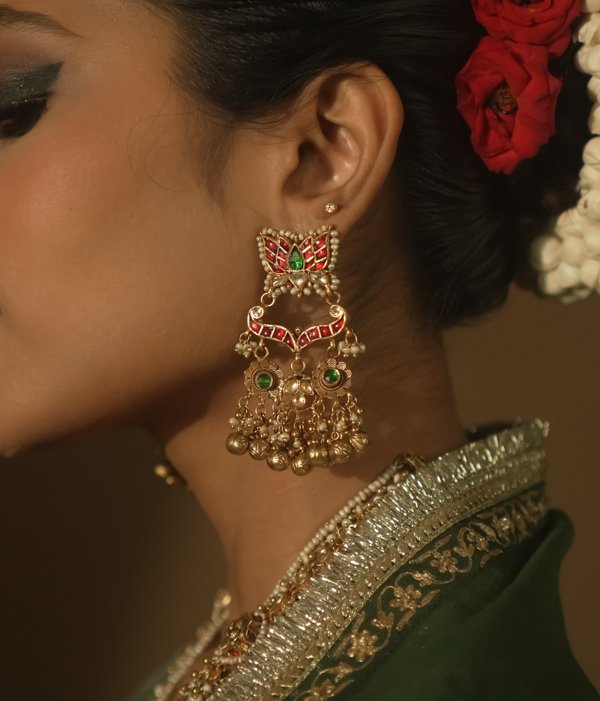 Gold earrings with red and green Kundan stones and dangling pearls.